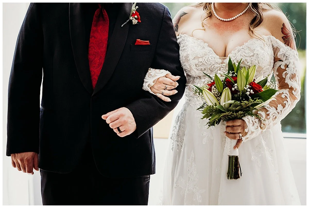  bride and groom closeup of arms around each other holding wedding bouquet before walking down the aisle. 