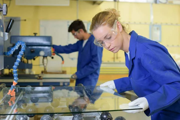 Workers manually inspecting a sheet of glass.