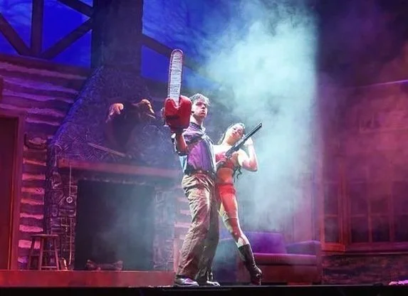 Chainsaw wielding Ash embracing Annie, an archaeologist that accidentally gets her clothing torn apart over the course of the musical. 