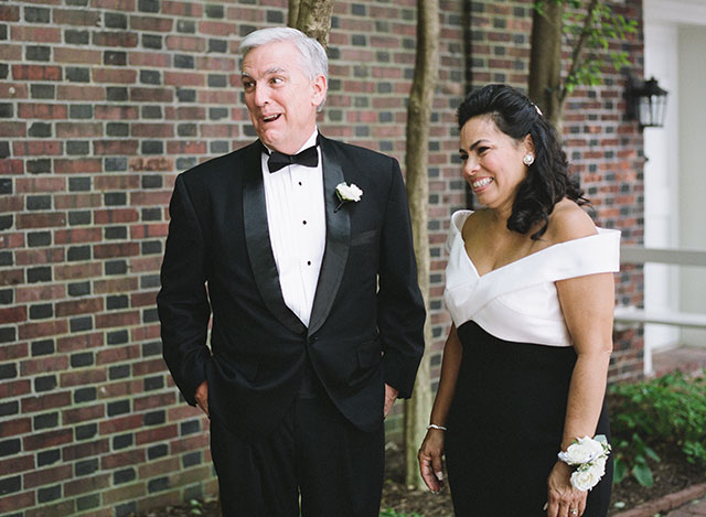 candid and sweet image of parents watching bride being photographed