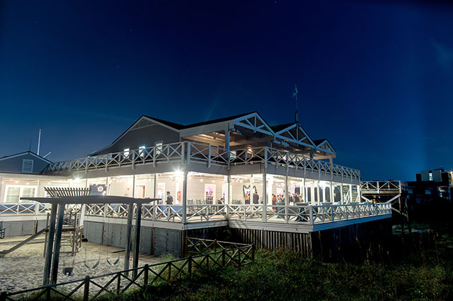 twilight shot of carolina yacht club reception, string lights and waterfront, sandy beach