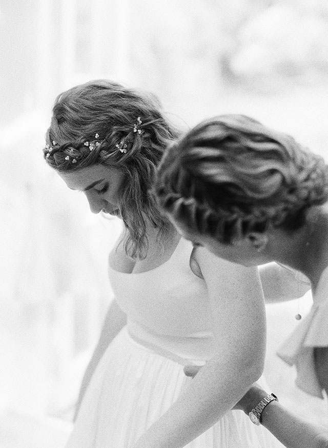 black and white film wedding photo of bride putting on wedding dress