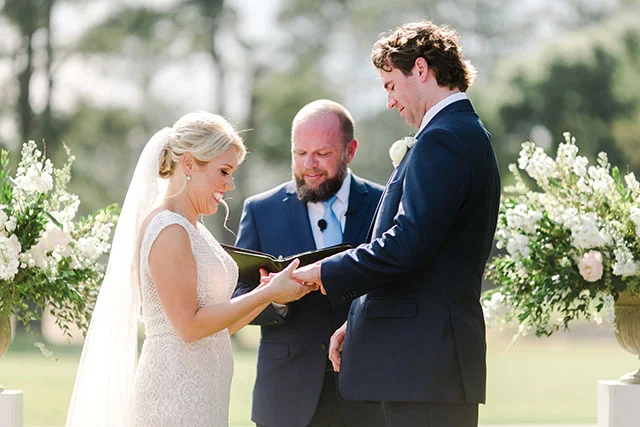 Bride puts ring on grooms finger by Sarah Der