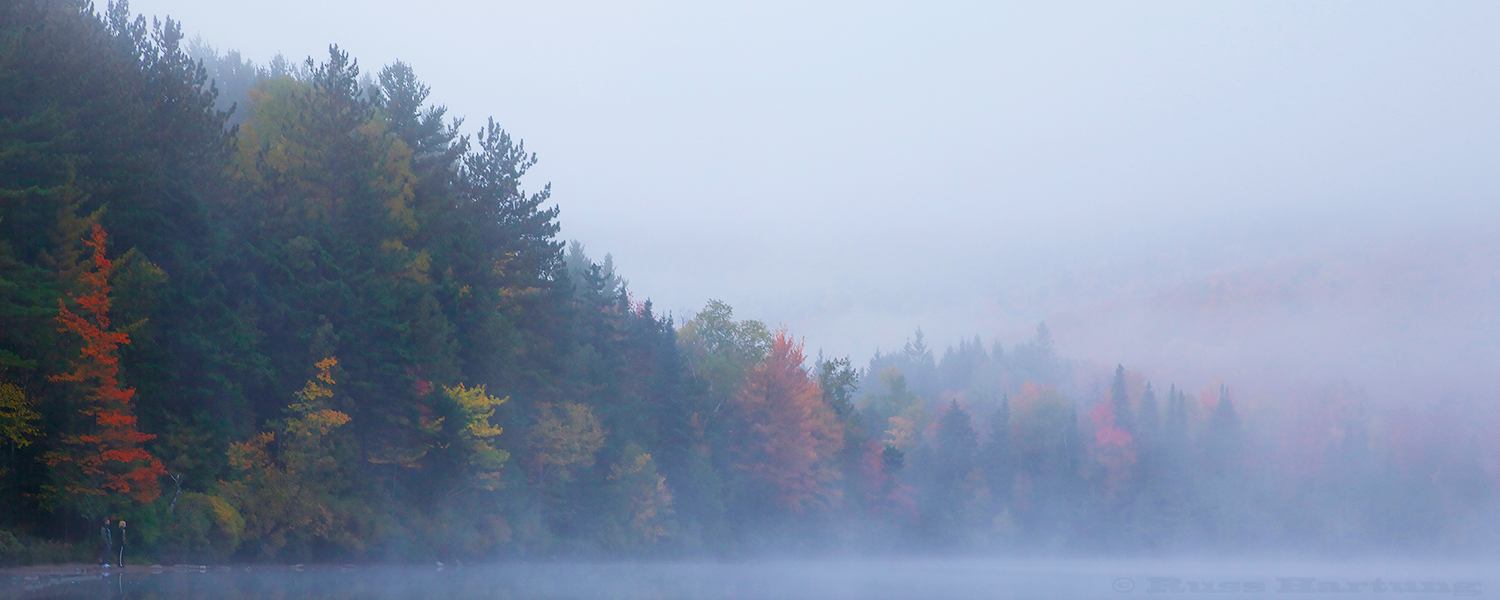 A couple enjoys the morning mist and the fall colors at Heart Lake in the High Peaks region of the Adirondacks. 