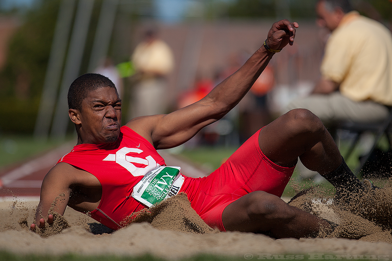 Steven Bell lands in the sand pit during the long jump competition at the Heptagonal Championships. 