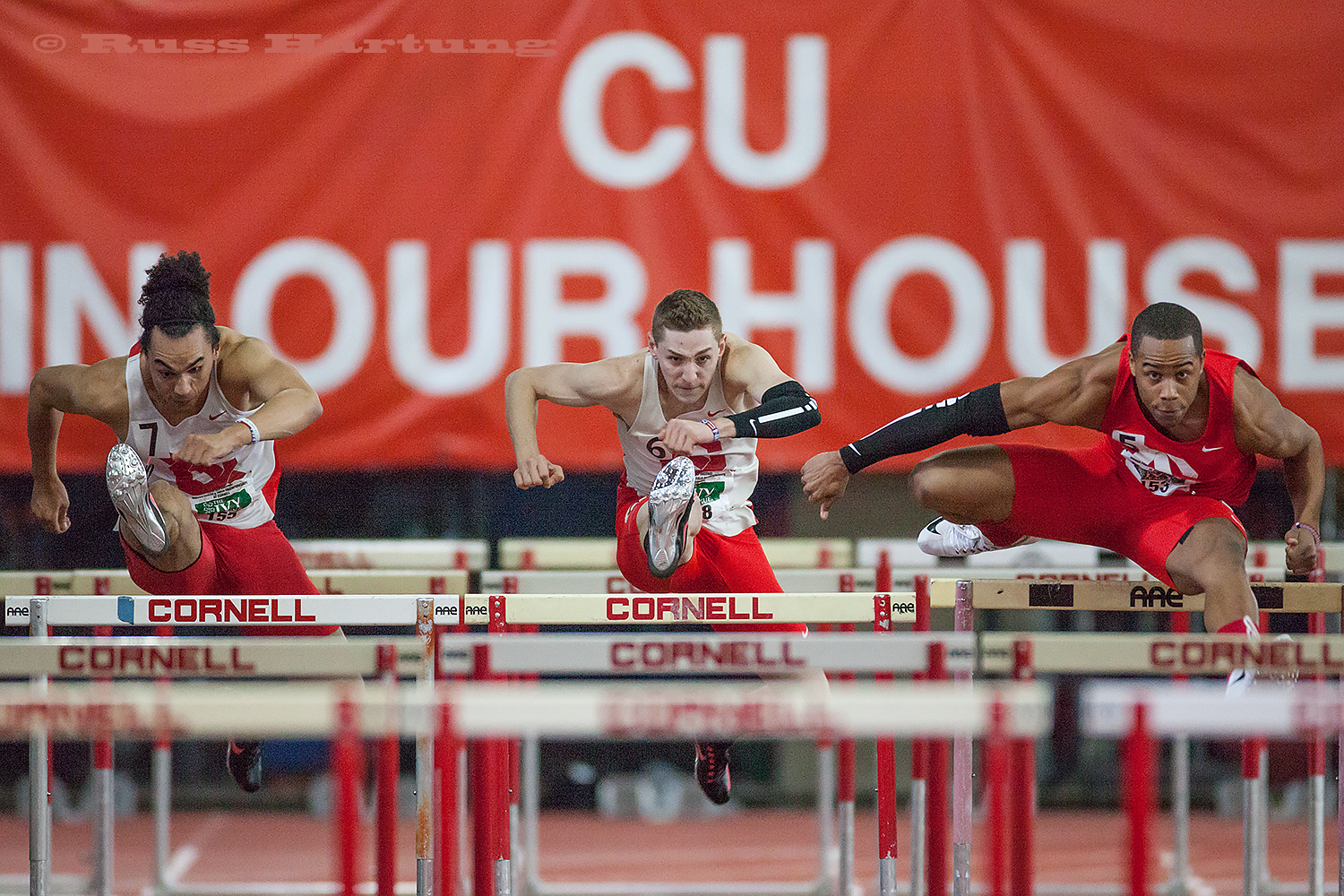 Two hurdlers are in synch while a third edges slightly ahead. 