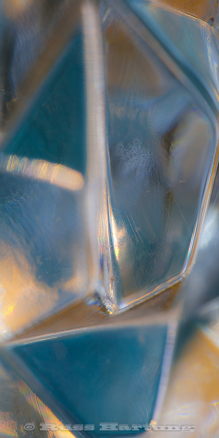 An extreme macro close-up of cut glass reflecting colored paper. 