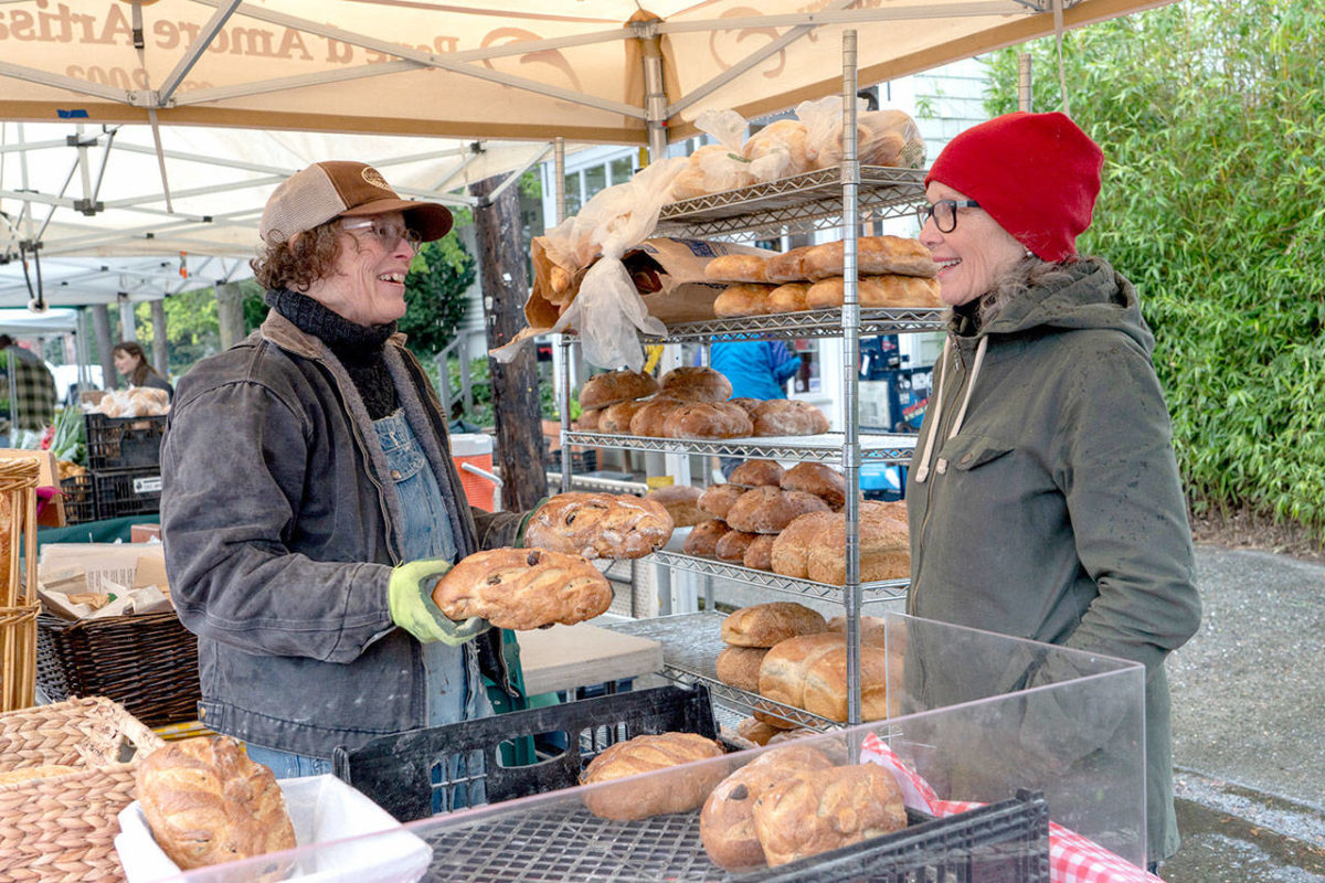 PORT TOWNSEND — Heather Hicks, left, and Linda Yakush, owner of Pane d’Amore bakery in uptown Port Townsend, prepare loaves of bread and sweet rolls for sale at the opening of the Port Townsend Farmers Market on Saturday.