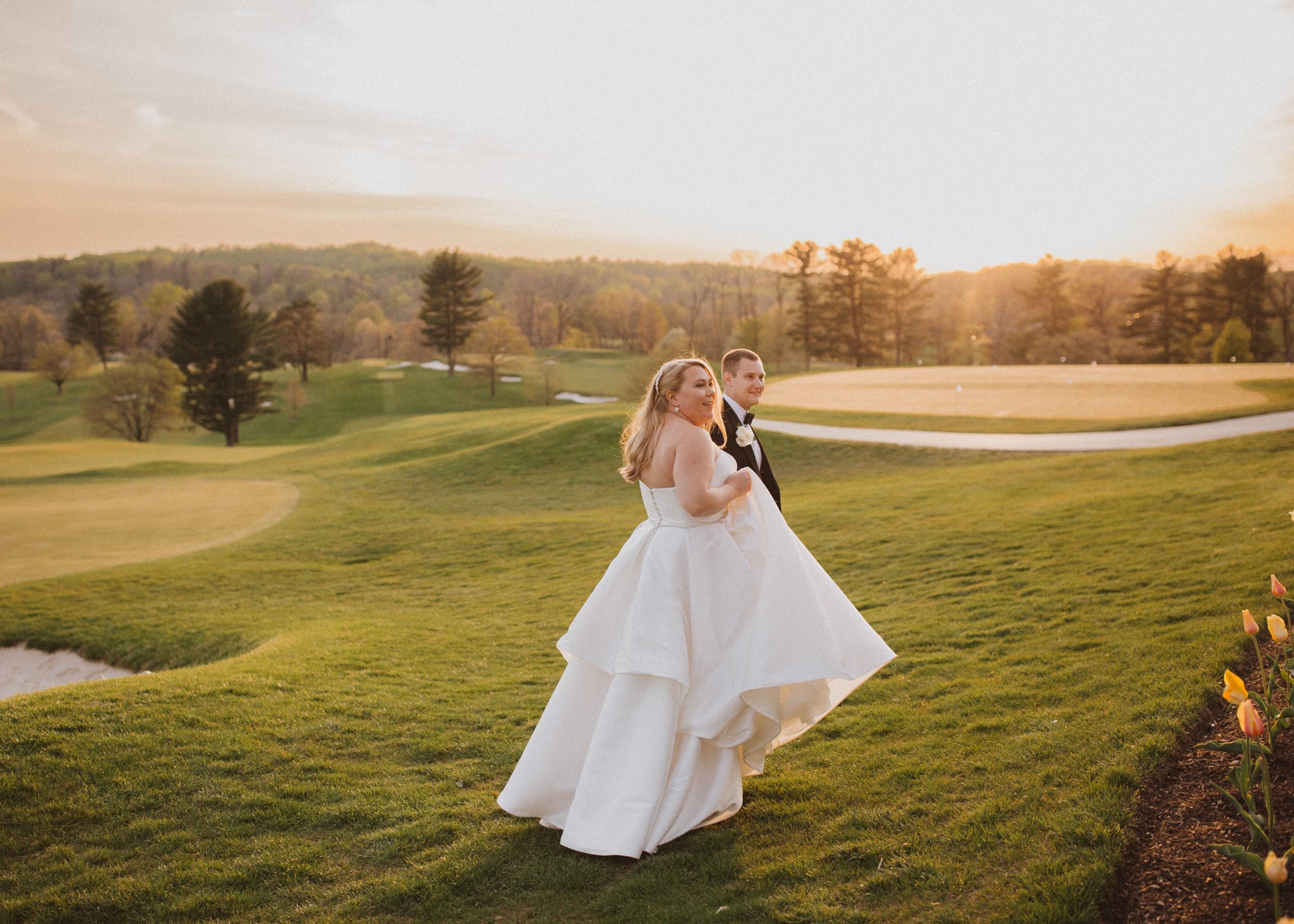 Bride in wedding dress walking with groom at Philadelphia golf course.