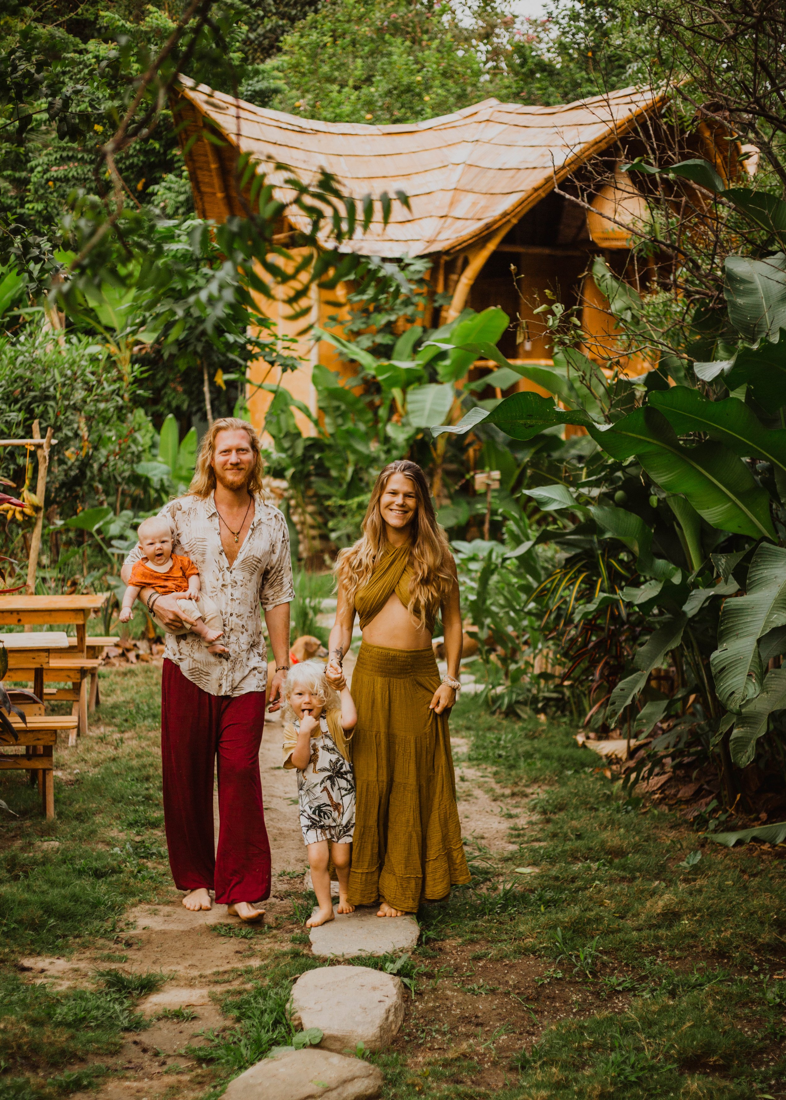 Mother, father and their two young children walking towards camera outside their jungle house Colombia's Caribbean region.