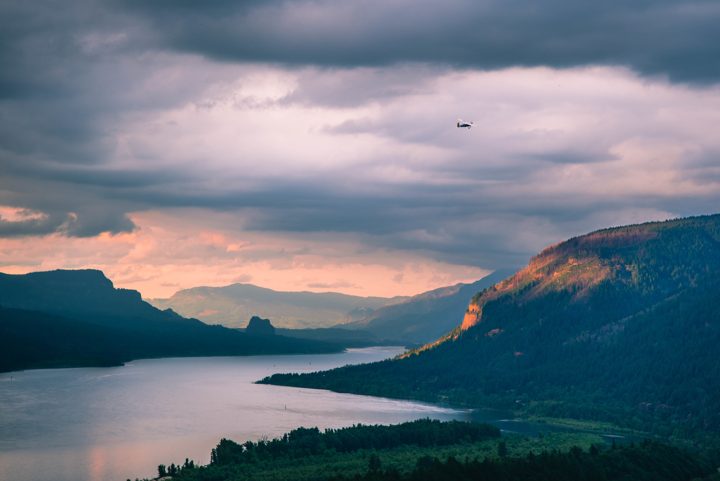 A small plane flies over the Columbia River Gorge at sunset
