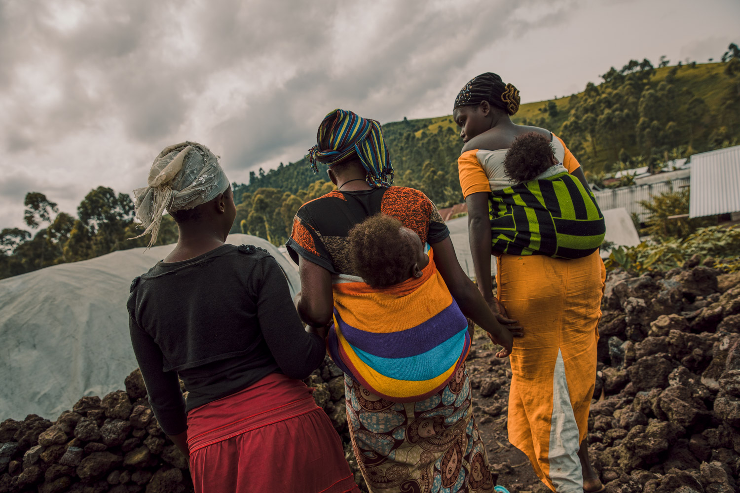 Three young former child brides and victims of sexual violence walk together through an IDP camp in North Kivu.