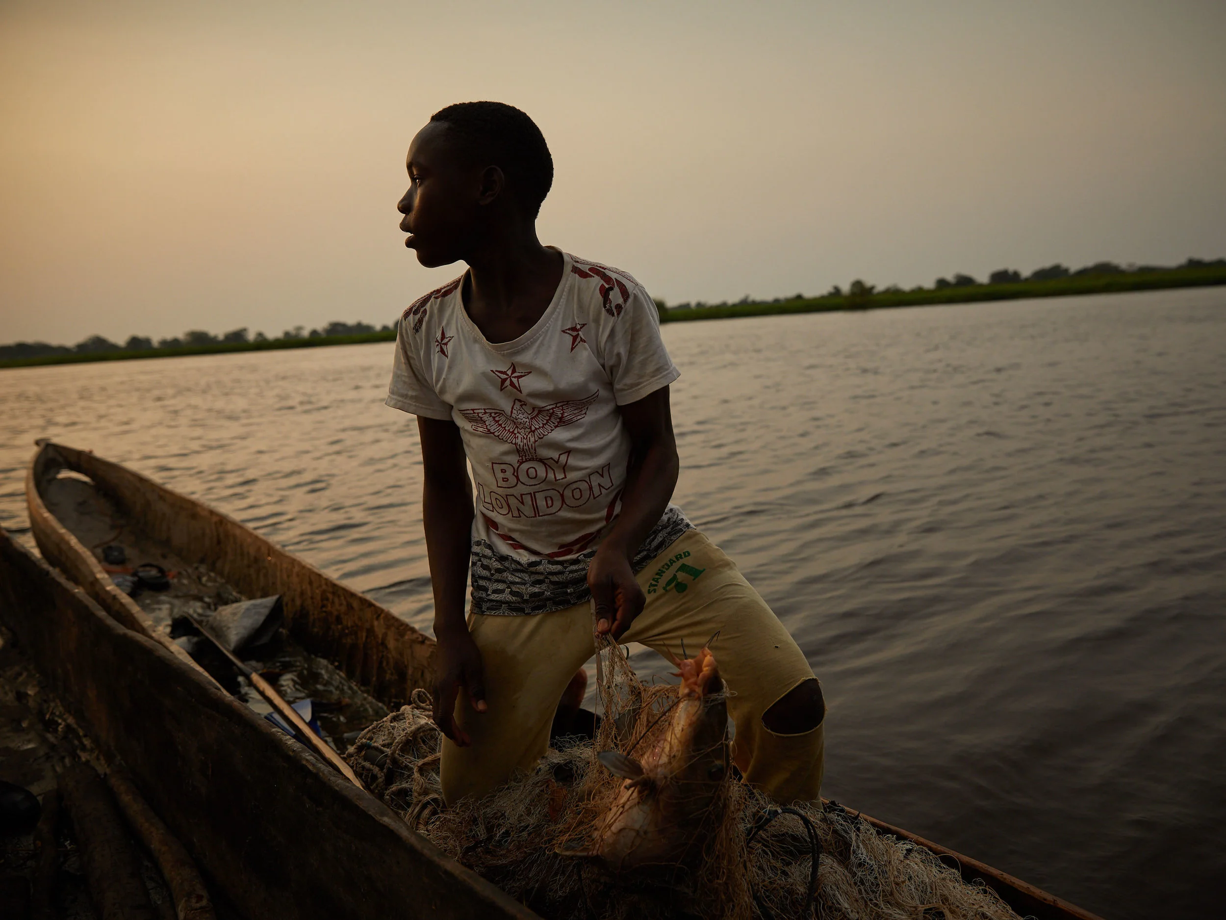 A boy sells his catch of the day mid-stream of the Congo River, Equateur Province. Venomous species of snakes pose a risk of bites when caught in nets or hunting along river banks. 