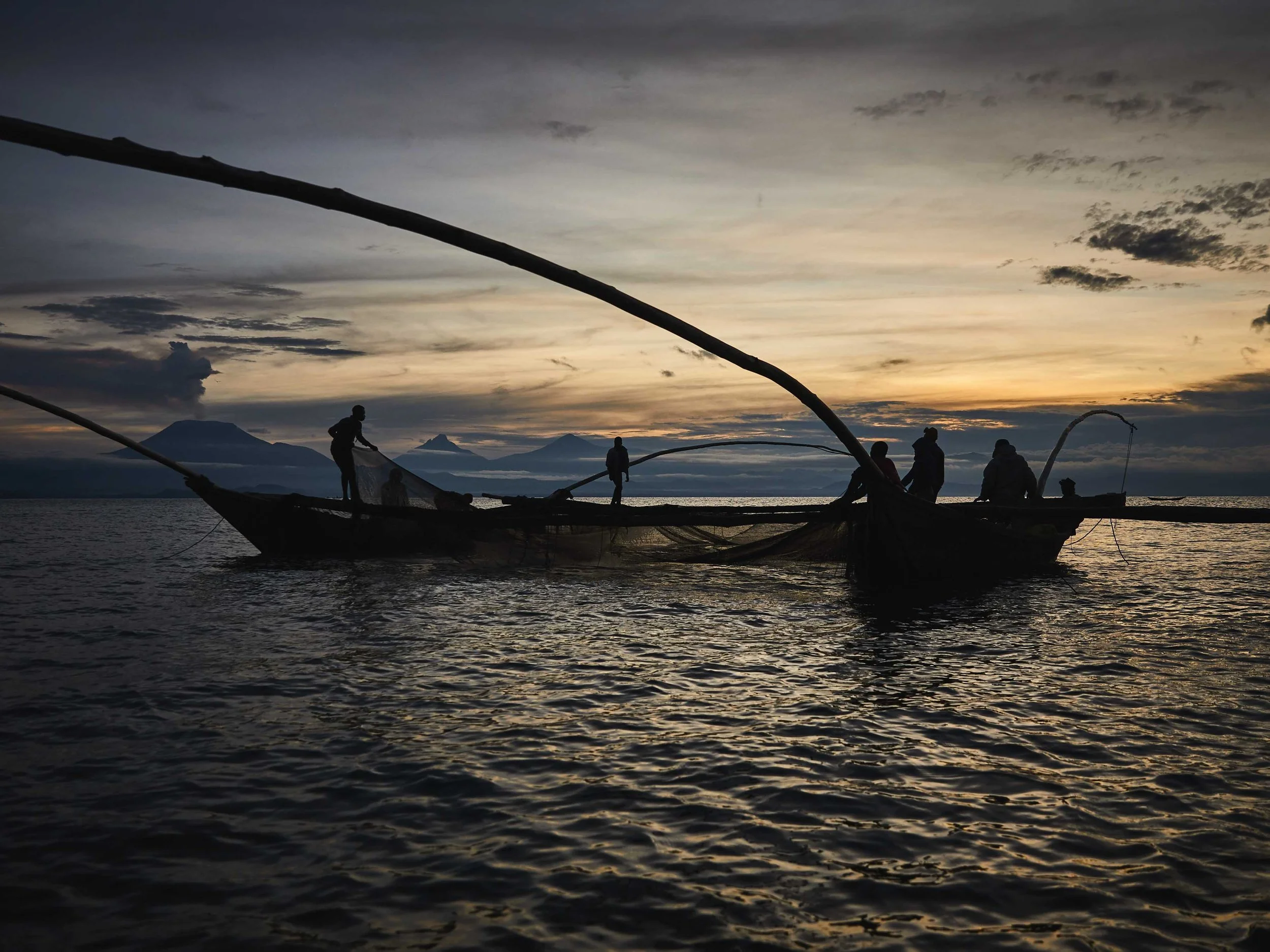 Fishing crews at dawn on Lake Kivu, silhouetted by the Virunga volcanoes. South Kivu, DRC.