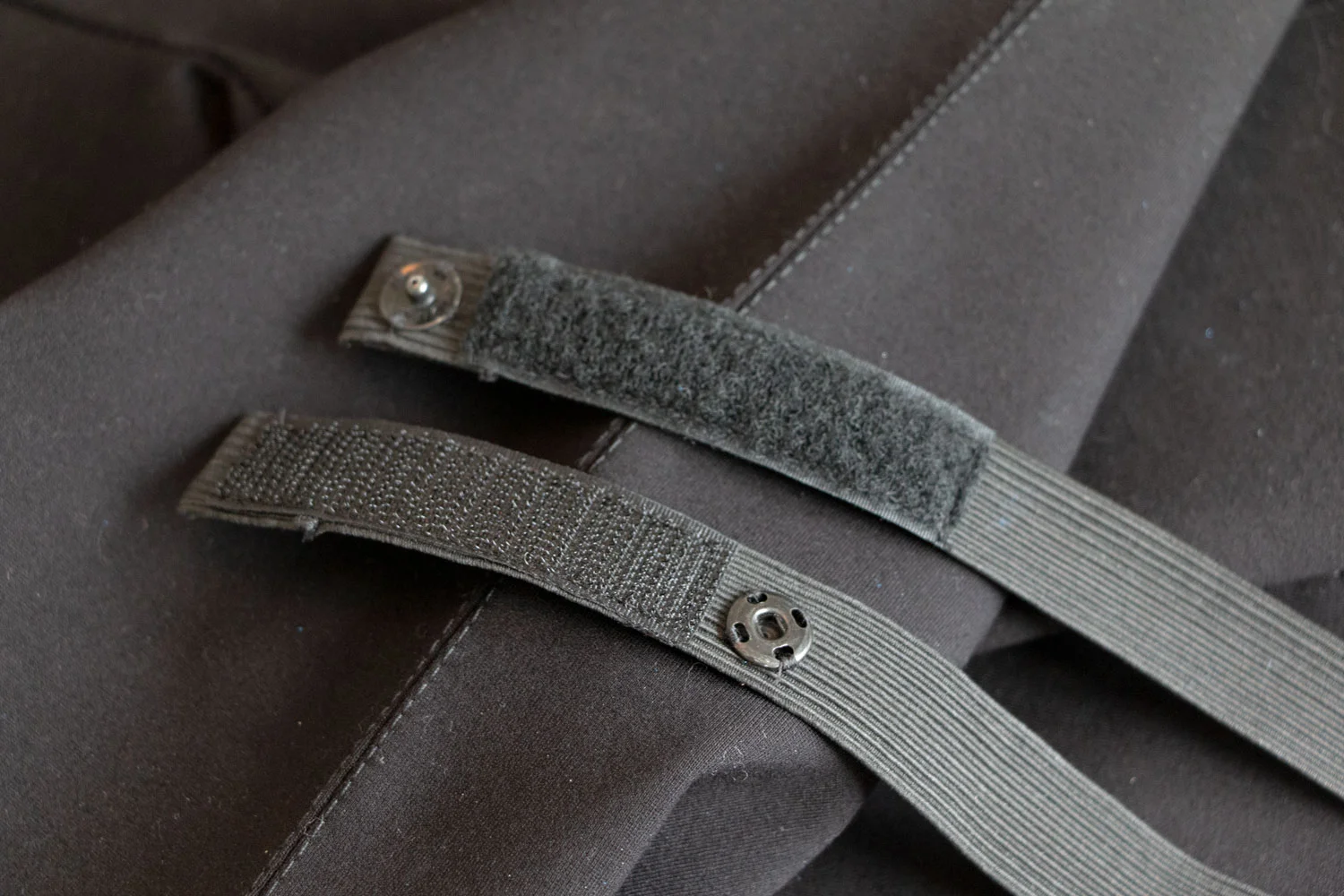 Single straps with snap to replace previous velcro and hook and eye closure. Old pants featured a single strap that would Velcro underneath with a hook and eye on top. Harder to come loose but harder for Jason to hook.