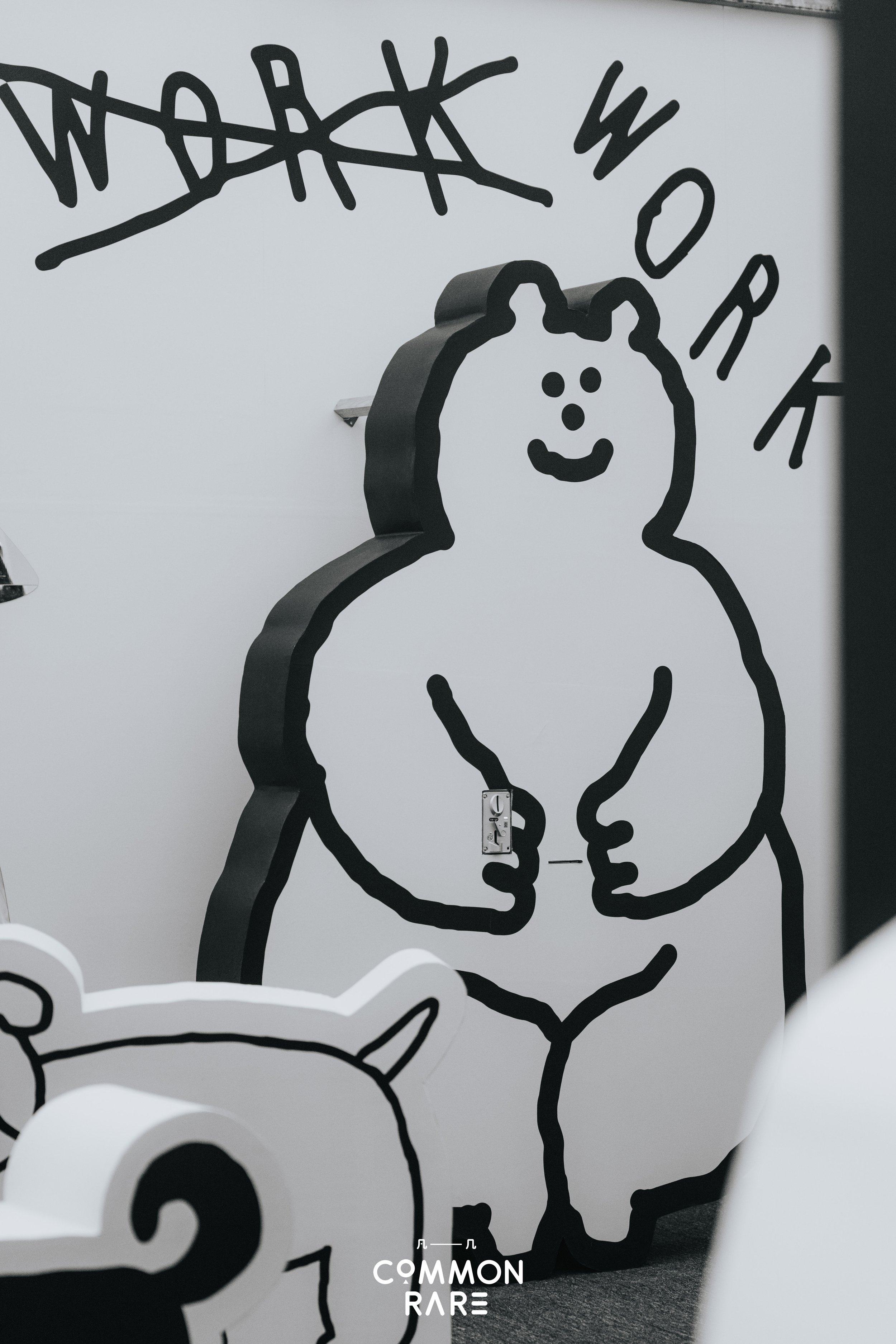 A wall decorated with black outline drawings of a girl with pigtails and a question mark, and a bear's head. The drawings are stylized and cartoon-like.