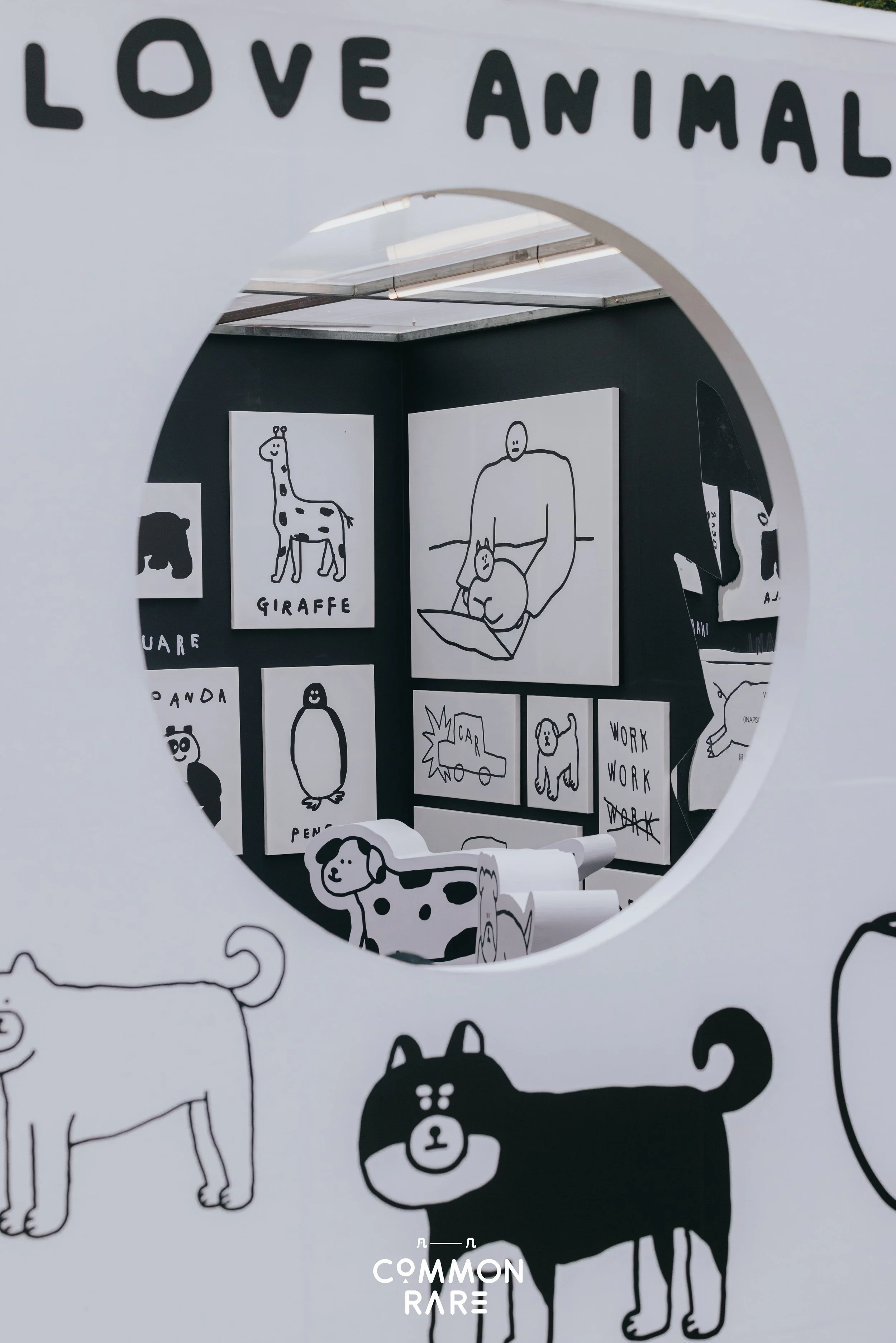 Display of black and white animal drawings, including a giraffe and a bear, in an exhibit titled 'Love Animal' at Common Rare. The drawings are simple line illustrations, some labeled with animal names.