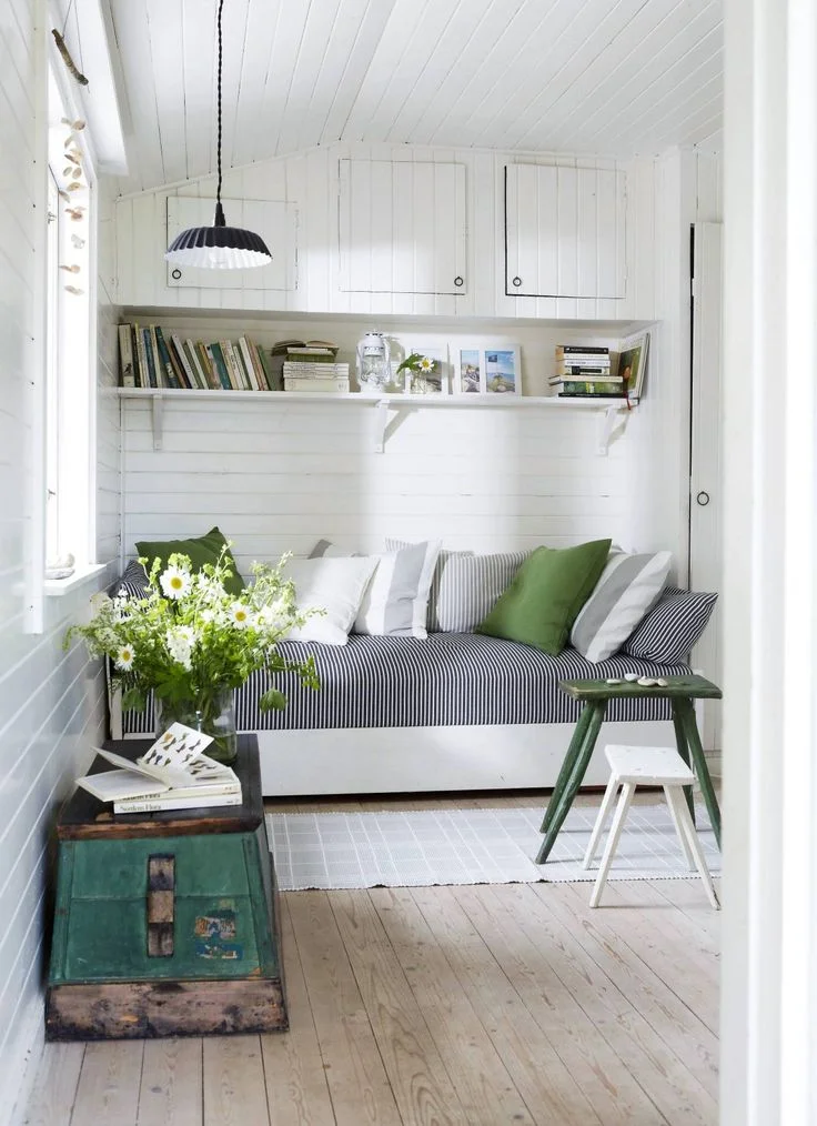 A snug space with a day bed, mixing modern textiles with antique features. Nordique loves the effect of the splash of green added to this calm white space. Image source
