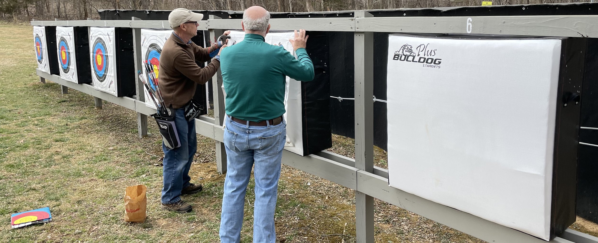   John Morgan and Mike Capps pin target faces onto the new targets.   