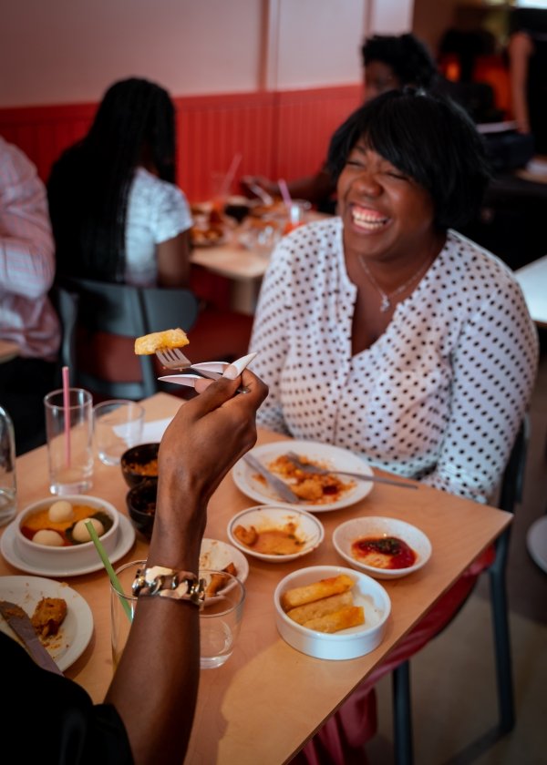 A Chuku''s guest laughing over their meal with a friend
