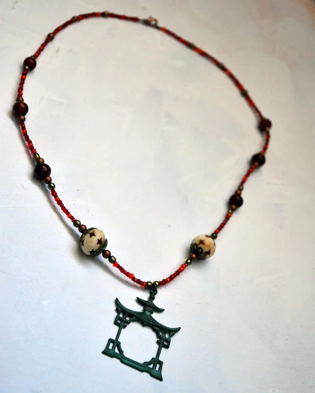 Necklace featuring Verdigris Patina Pagoda Charm and Red Glass Beads