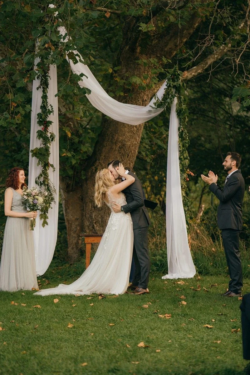 outdoor-hudson-valley-ceremony-fabric-in-tree-first-kiss-with-garland.jpg