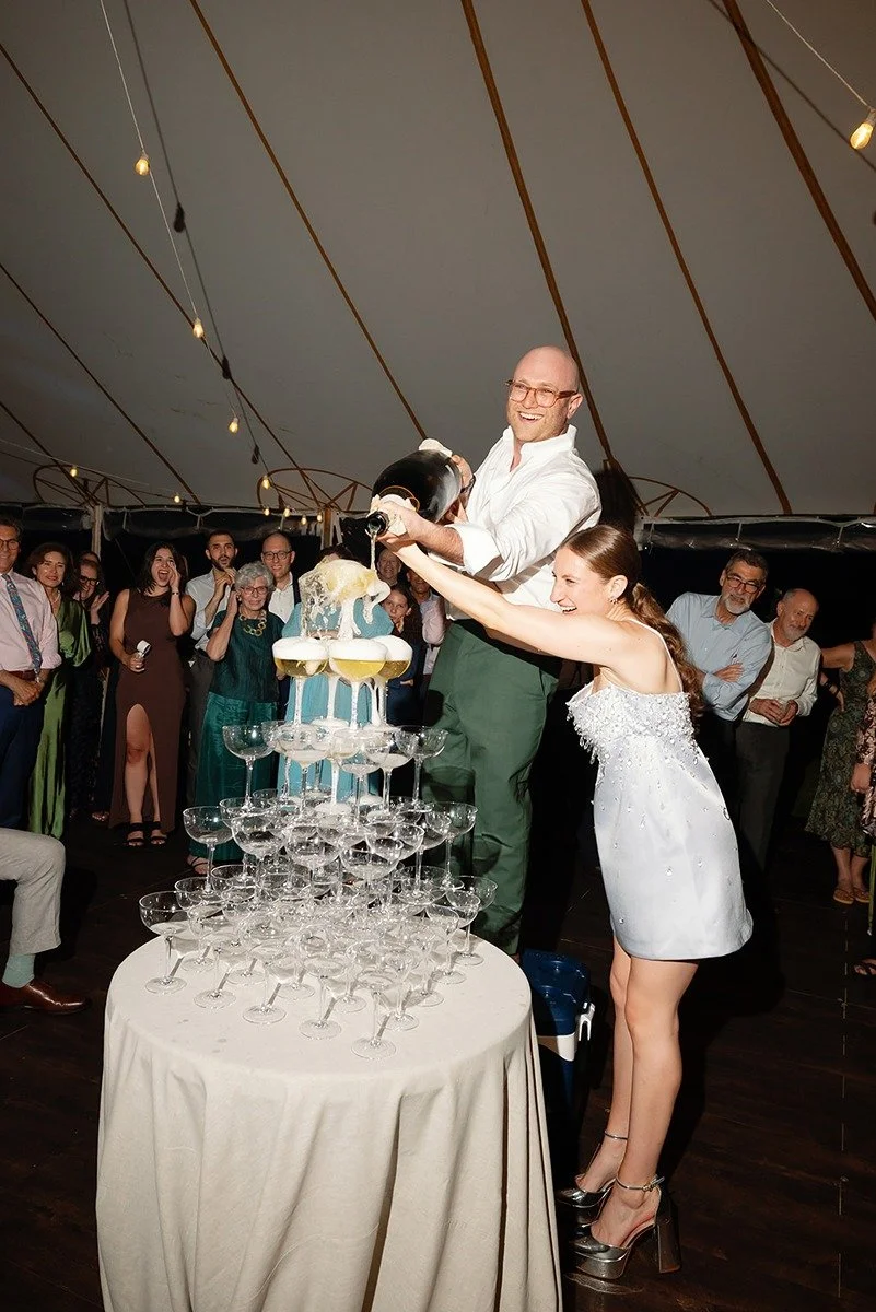 bride-and-groom-pouring-magnum-champagne-bottle-over-champagne-tower