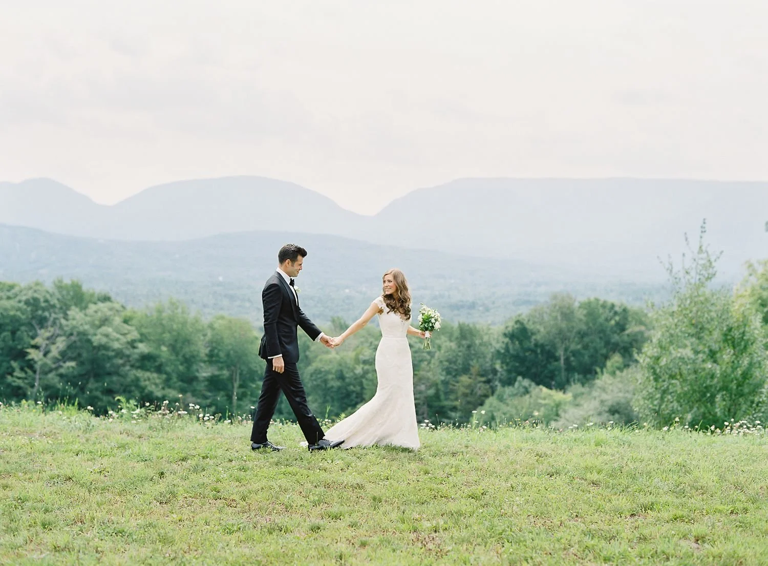 bride-and-groom-holding-hands-walking-together-with-catskill-mountains-in-background