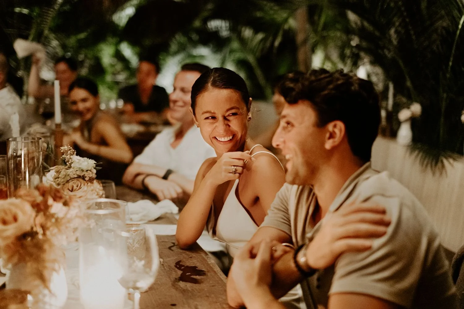 couple-laughing-enjoying-a-speech-surrounded-by-guests-at-their-tulum-mexico-wedding