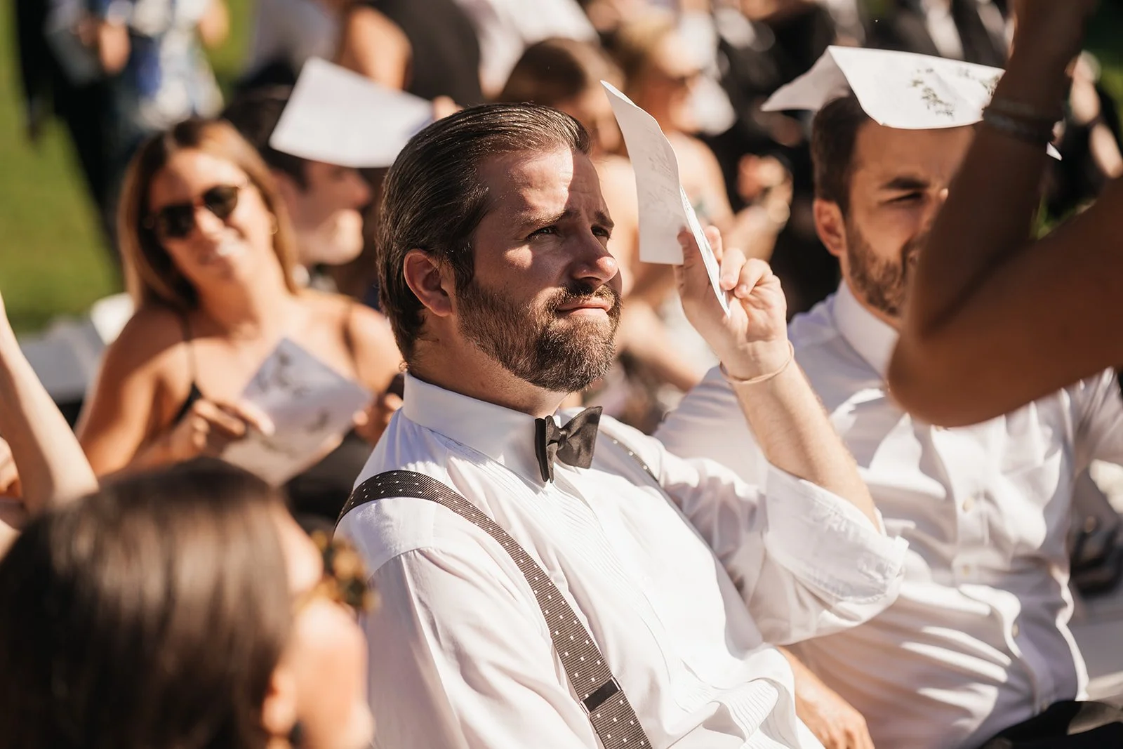 outdoor-wedding-ceremony-in-the-bright-sun-guests-using-random-things-to-shade-themselves