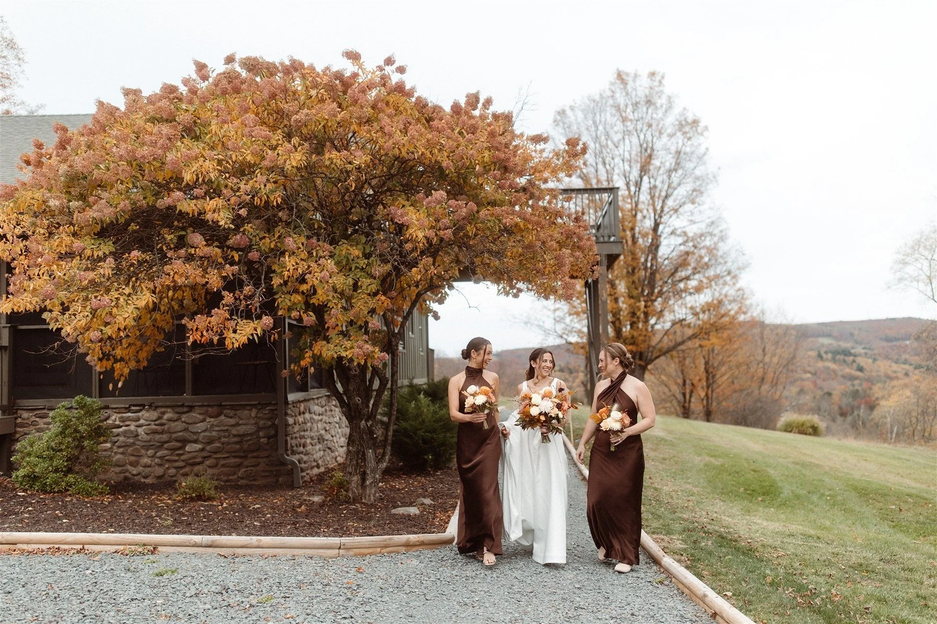 Bride-Walking-Under-A-Huge-Hydrangea-Tree-With-Maid-Of-Honor-And-Bridesmaid