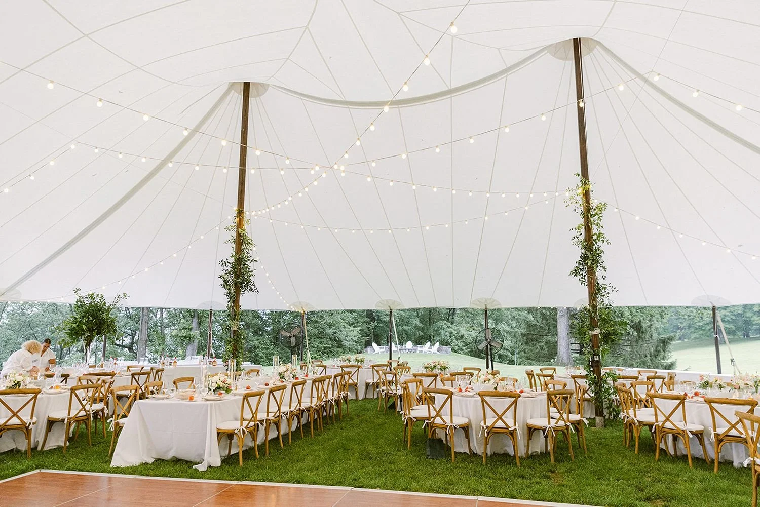sail-cloth-tide-water-tent-with-greenery-on-center-poles-smilax-cross-back-chairs-white-linens-and-peach-and-white-color-palette