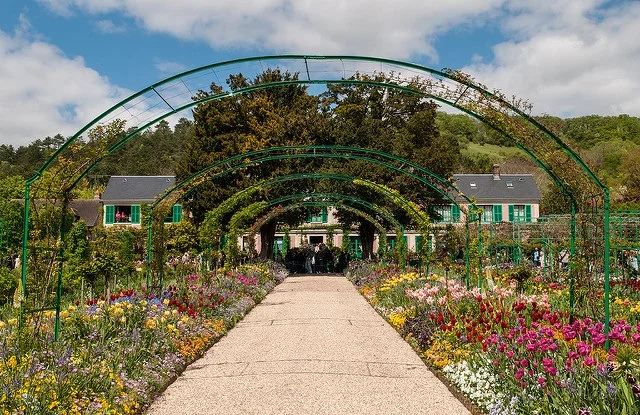 The arch-covered path at Giverny, Monet’s farmhouse in the background. — Ann & Michal/Flickr