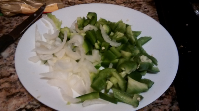 Step Three: As the sausage is browning, cut the whole green pepper (take out the seeds) and roughly a handful of onions. It doesn't have to be sliced and diced to perfection. I more-less chop at it.