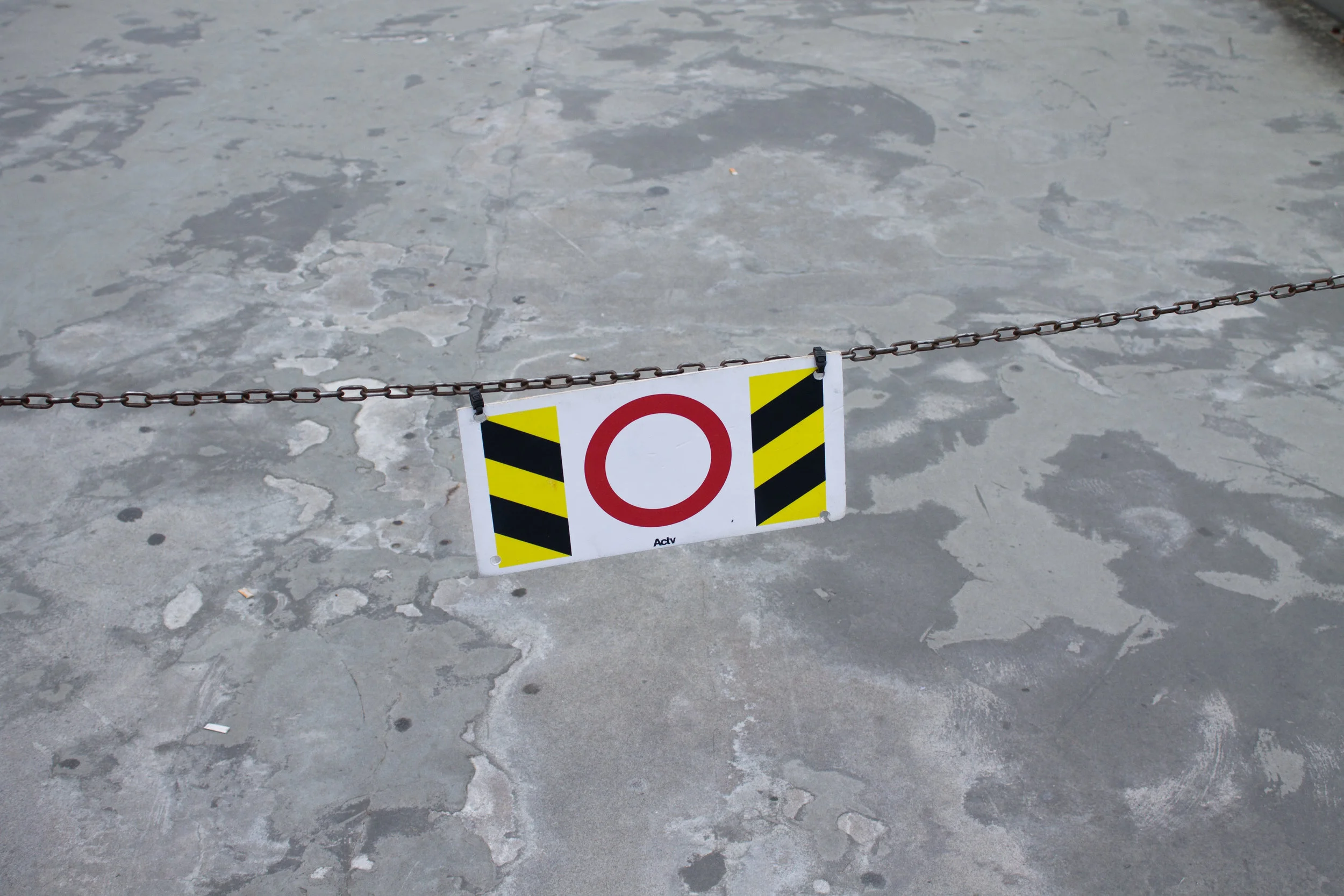 A chain link barrier with a sign indicating restricted access, placed on a worn concrete surface.
