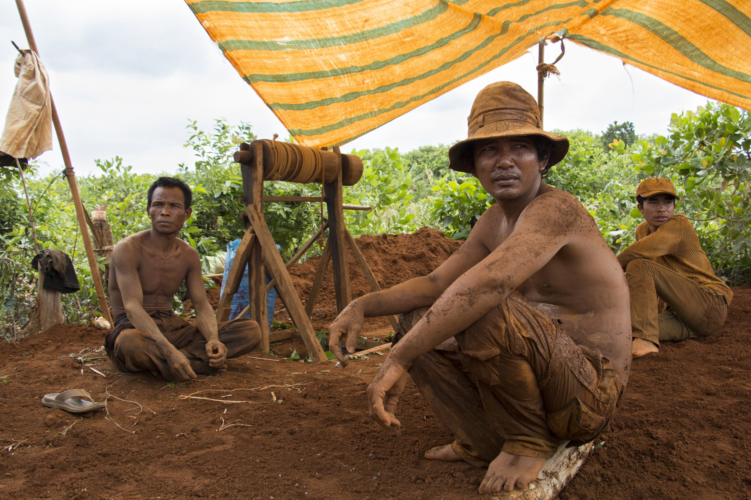 Three miners take a break from their work, mining for semi-precious stones, in the Ratanakiri province, Cambodia, January 2016. The miners earn their livelihood selling the zircon, amethyst and onyx stones they find. 