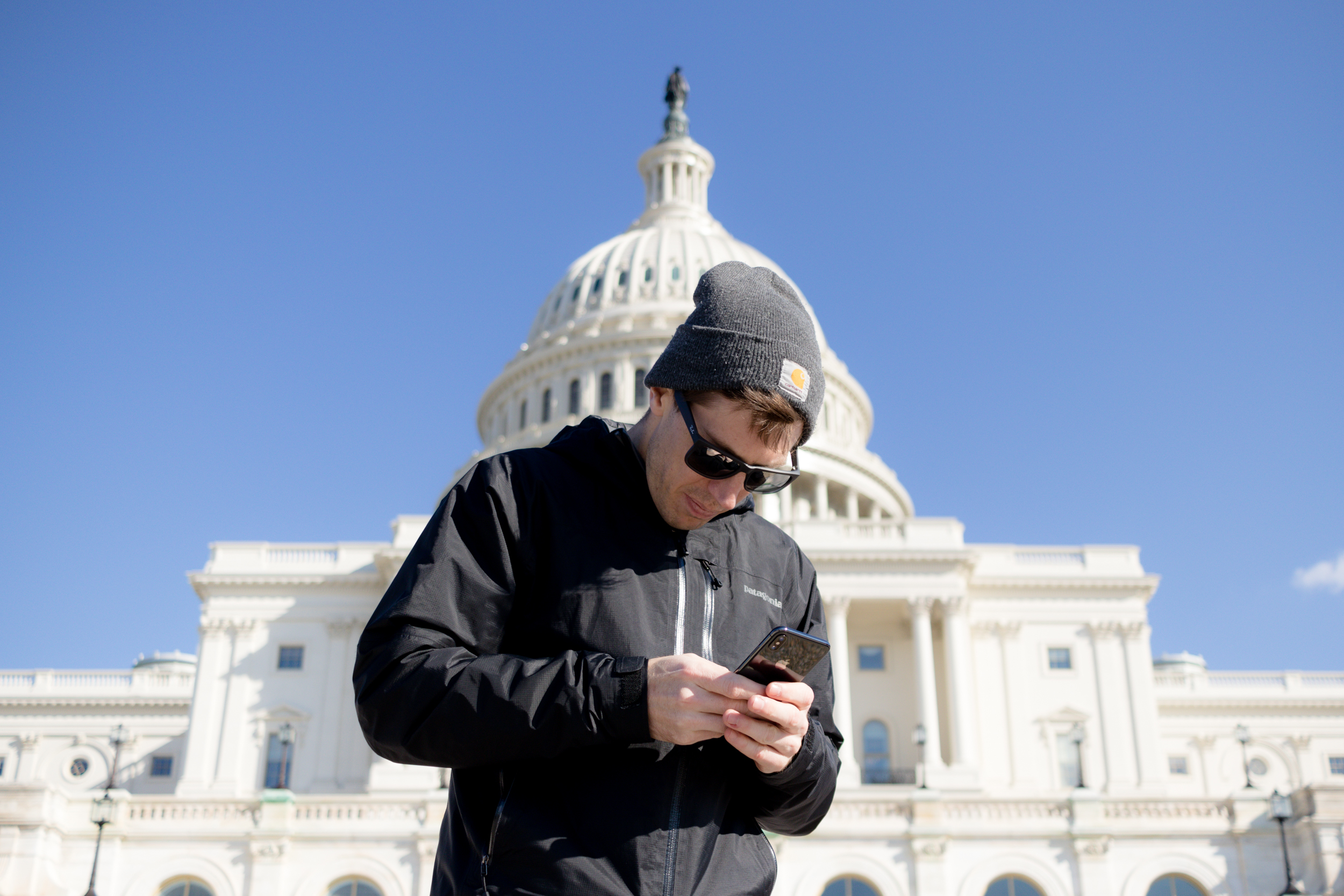 Shay on his phone in front of an important government building (Photo 2 of 3)