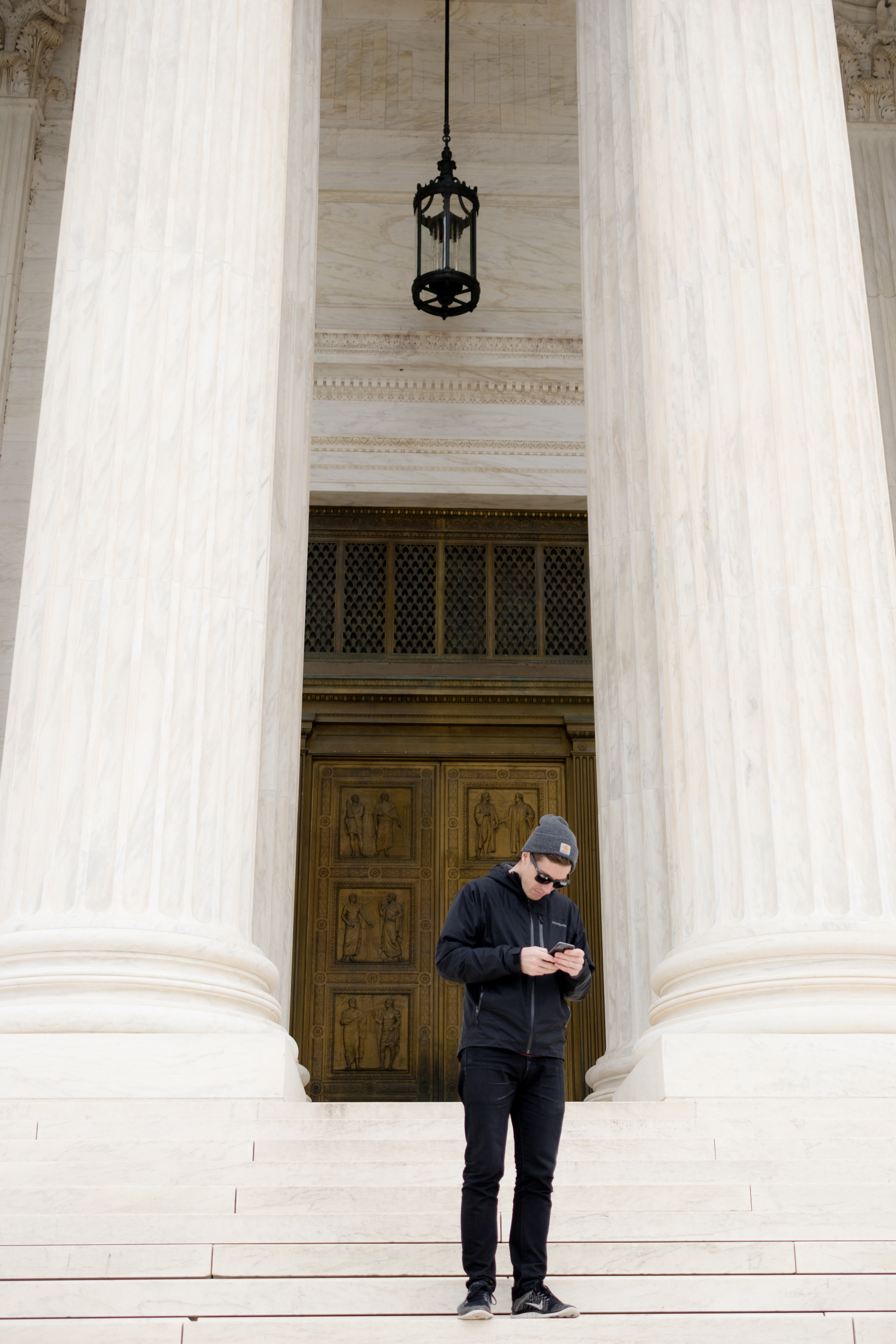 Shay on his phone in front of an important government building (Photo 3 of 3)