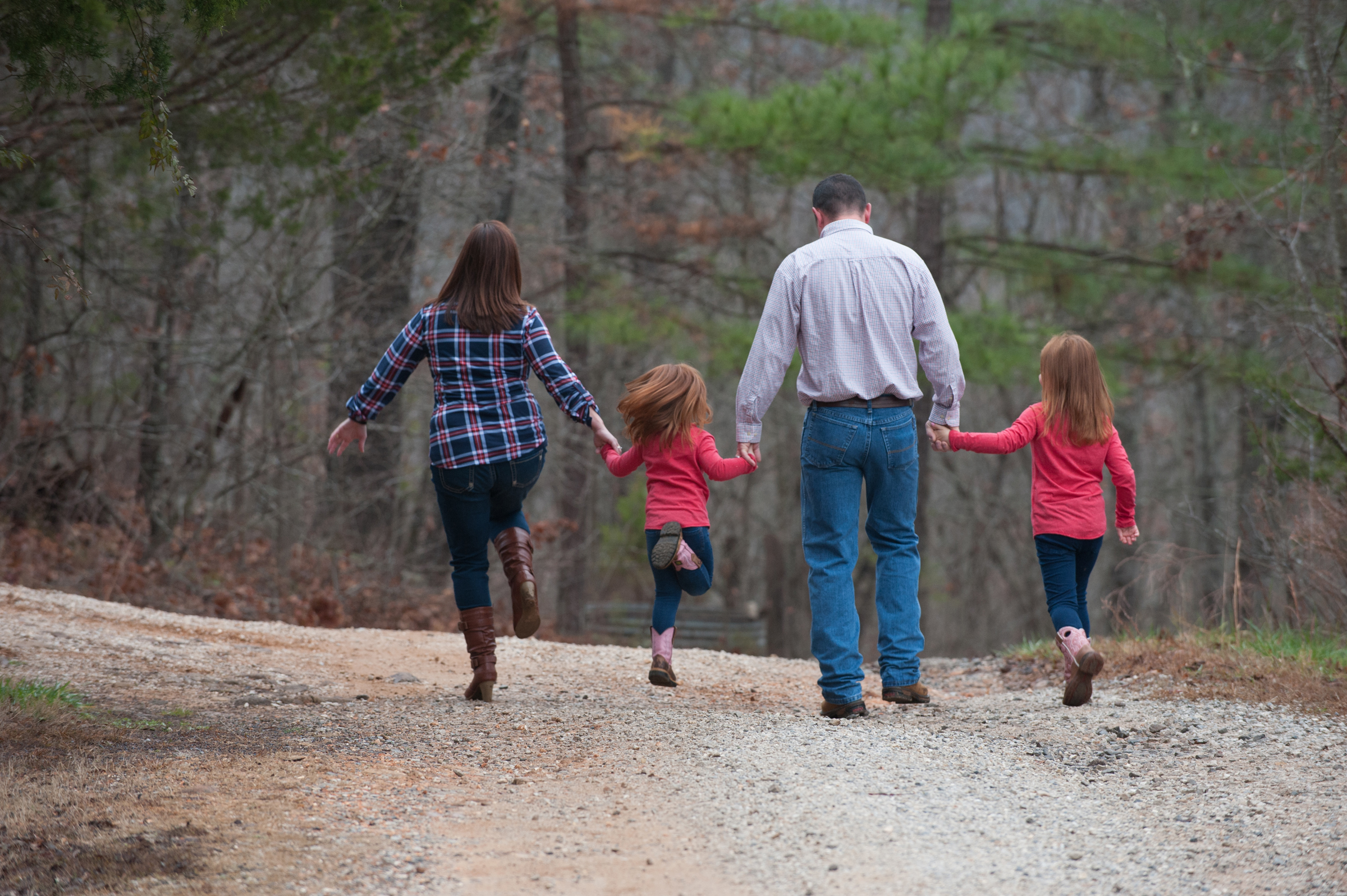 family of four walking down a dirt road holding hands