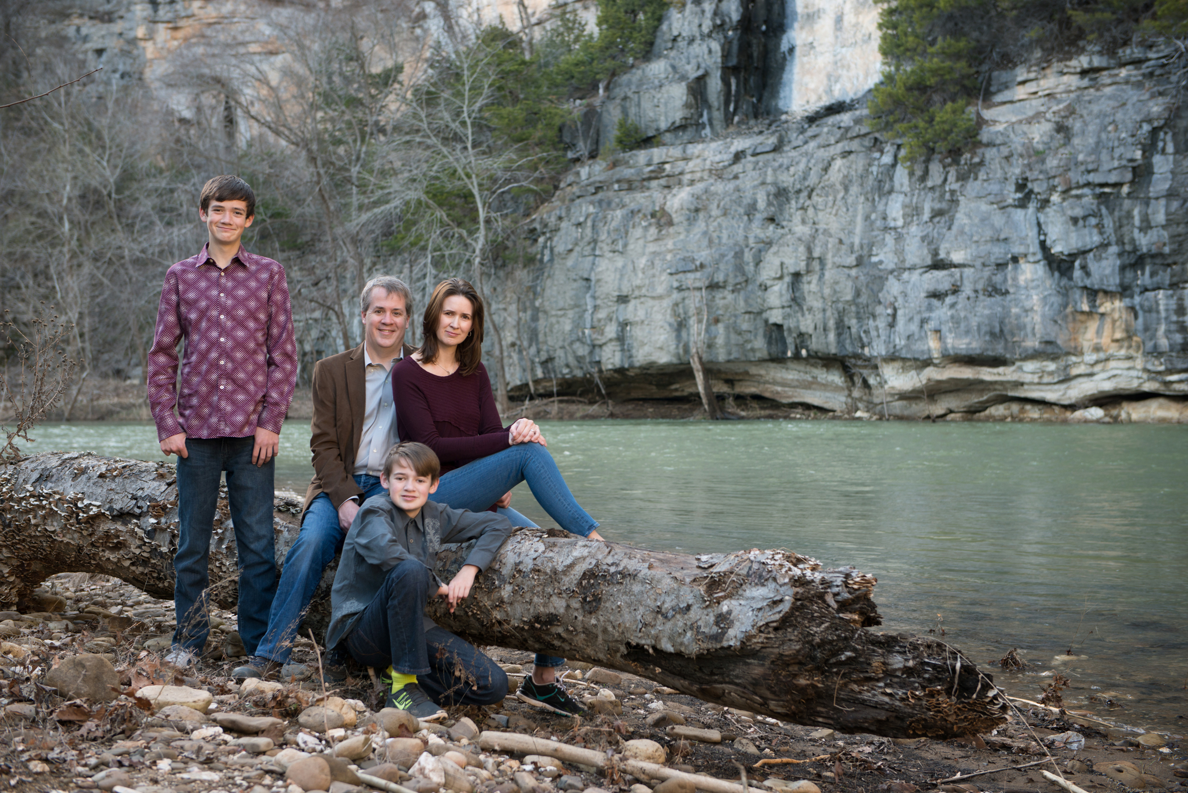 family of four sits on a log beside the Buffalo River