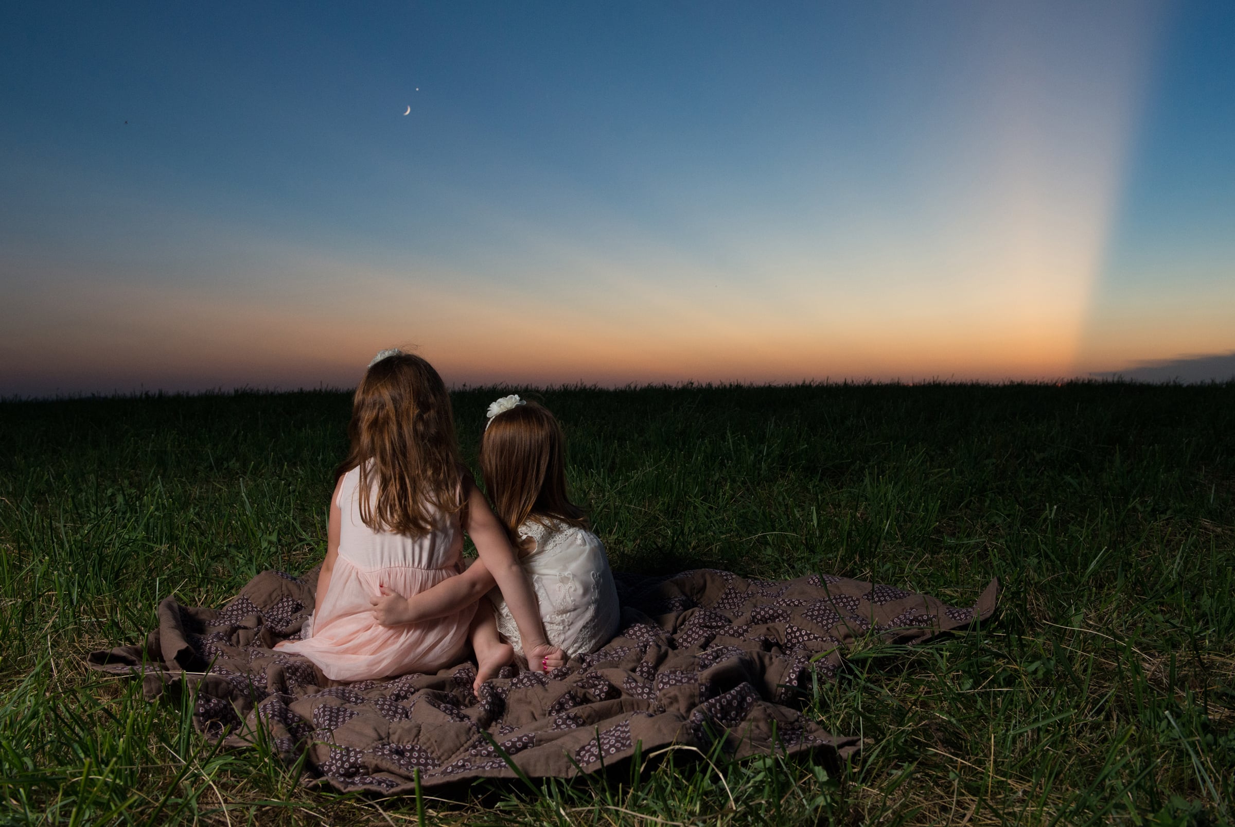 Two little girls watch a beautiful sunset on a mountain top