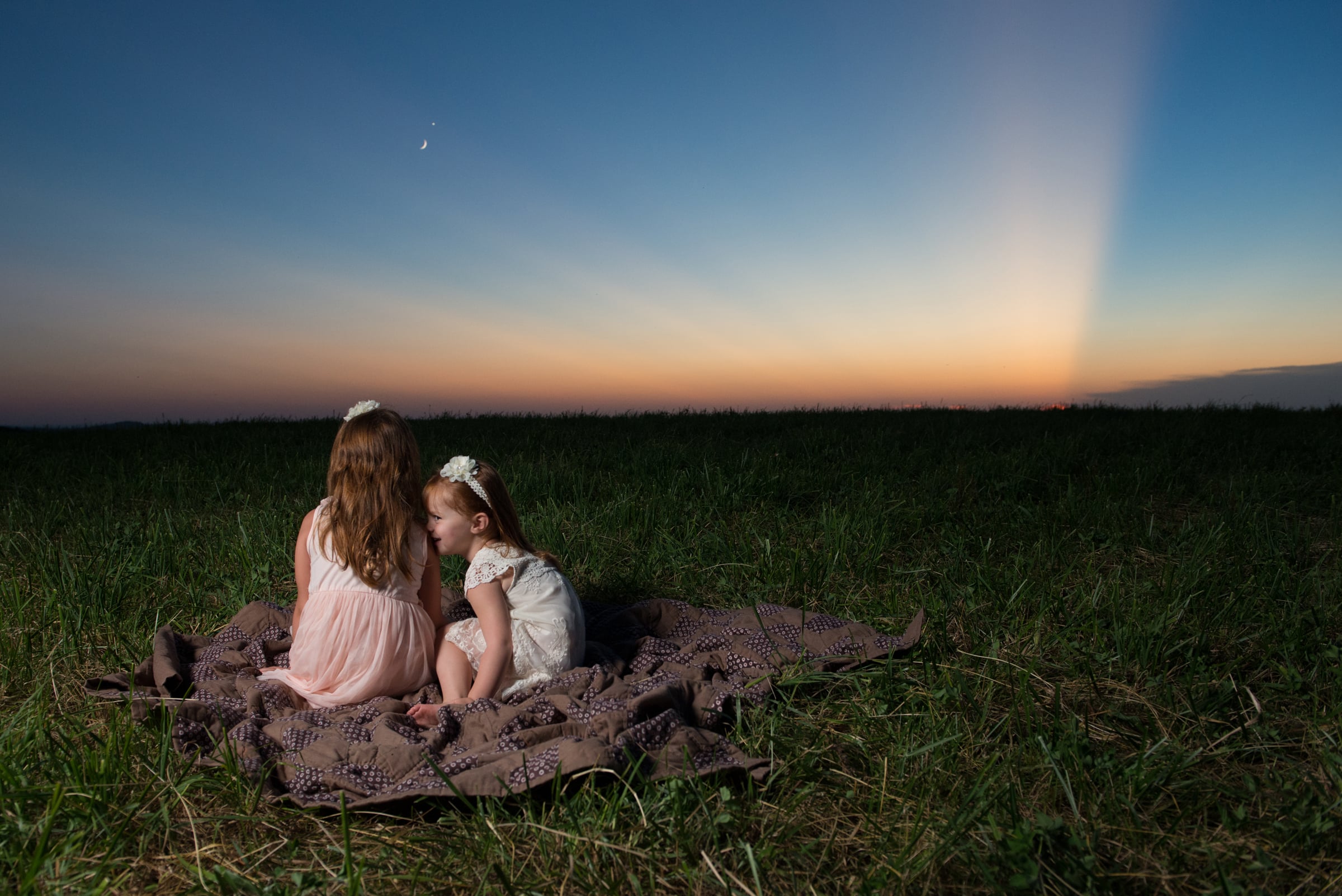 Two little girls watch a beautiful sunset on a mountain top