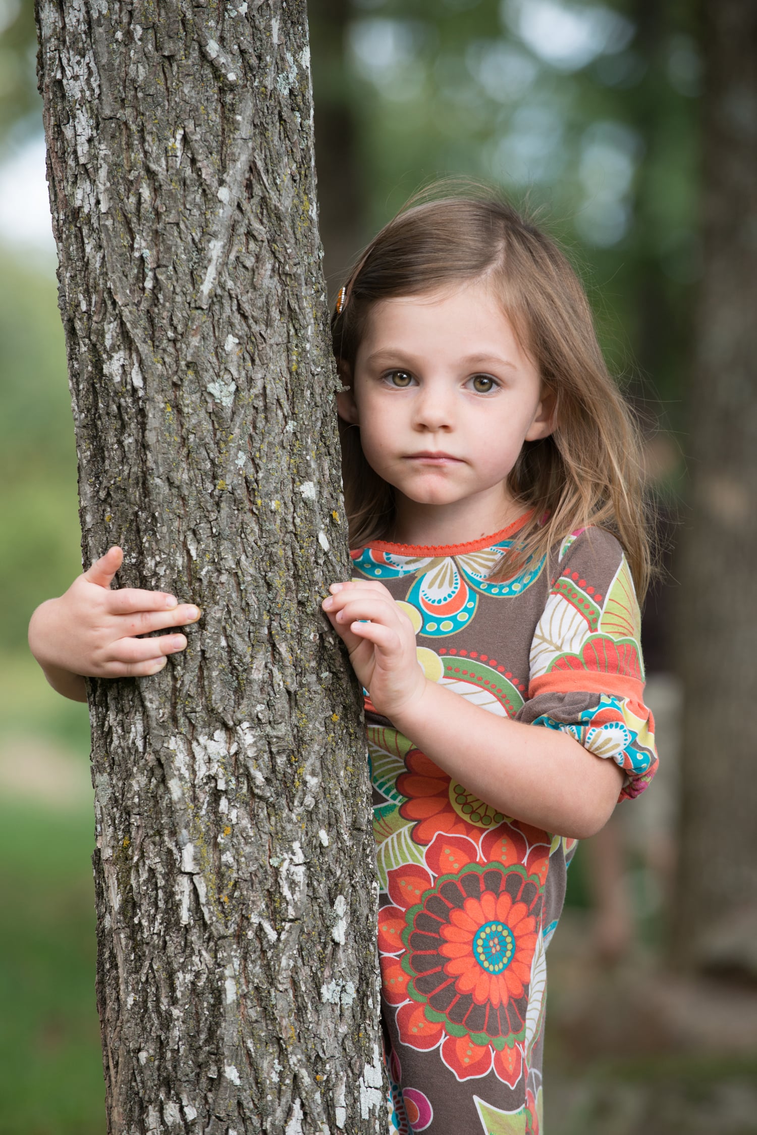 Little girl hiding behind tree