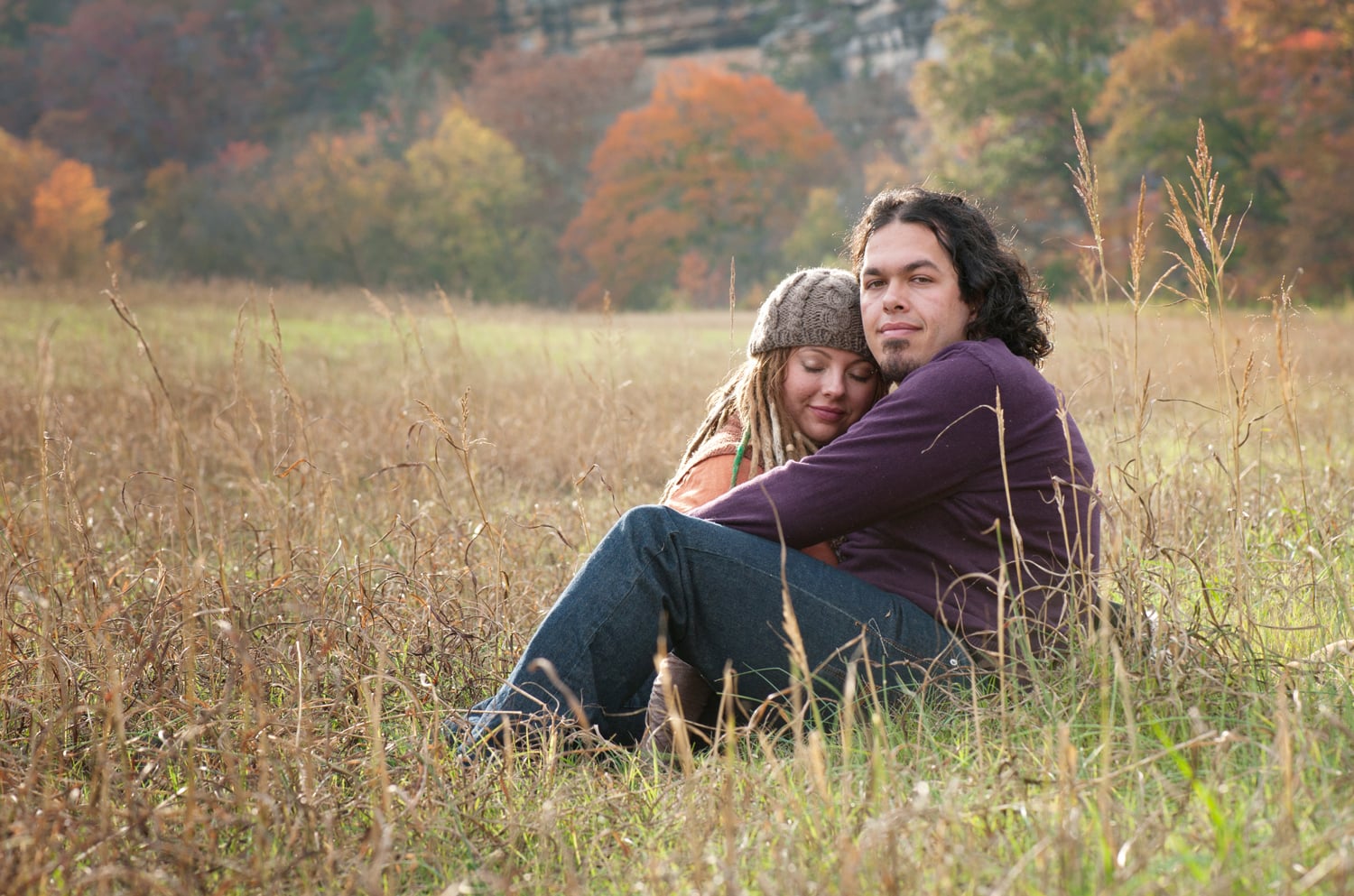 Engaged couple sitting in a meadow at sunset