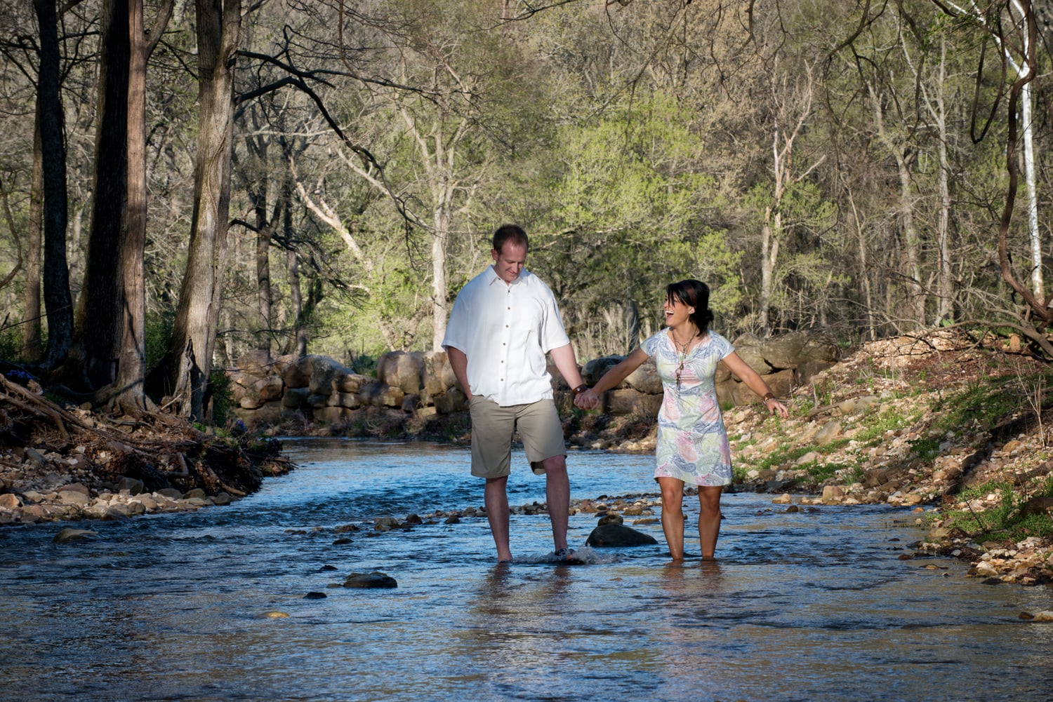 Laughing couple walks in a stream together