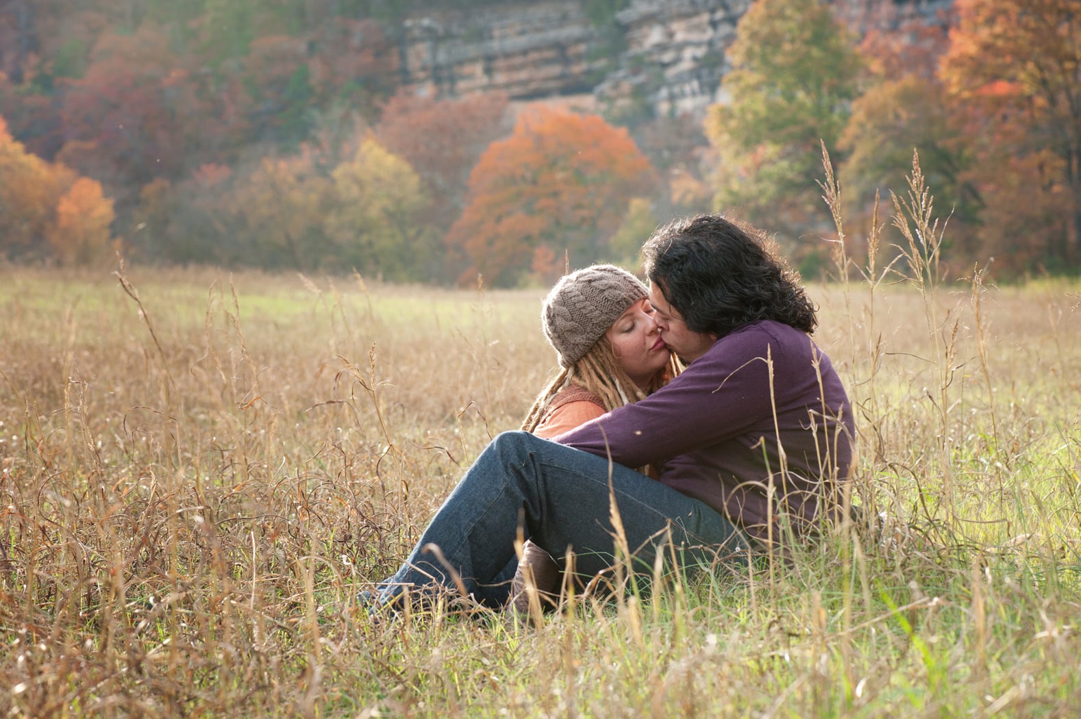 Couple kisses in a meadow in fall