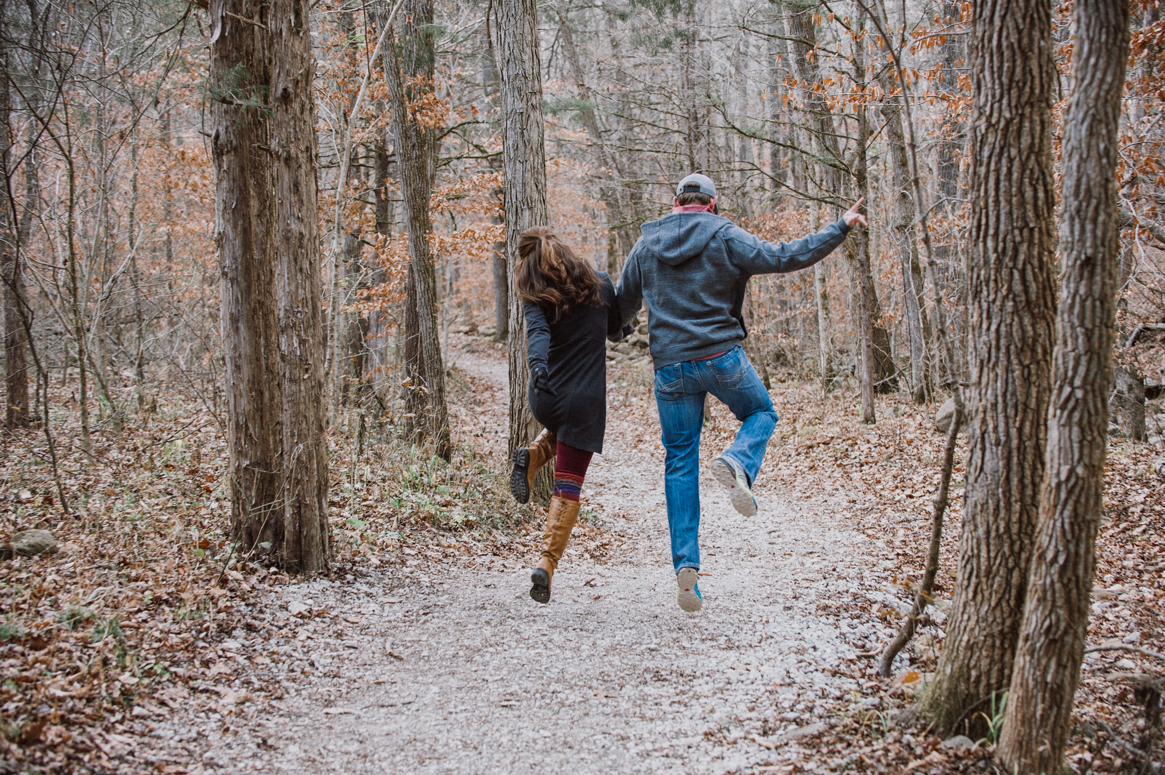 Couple skipping down a wooded trail