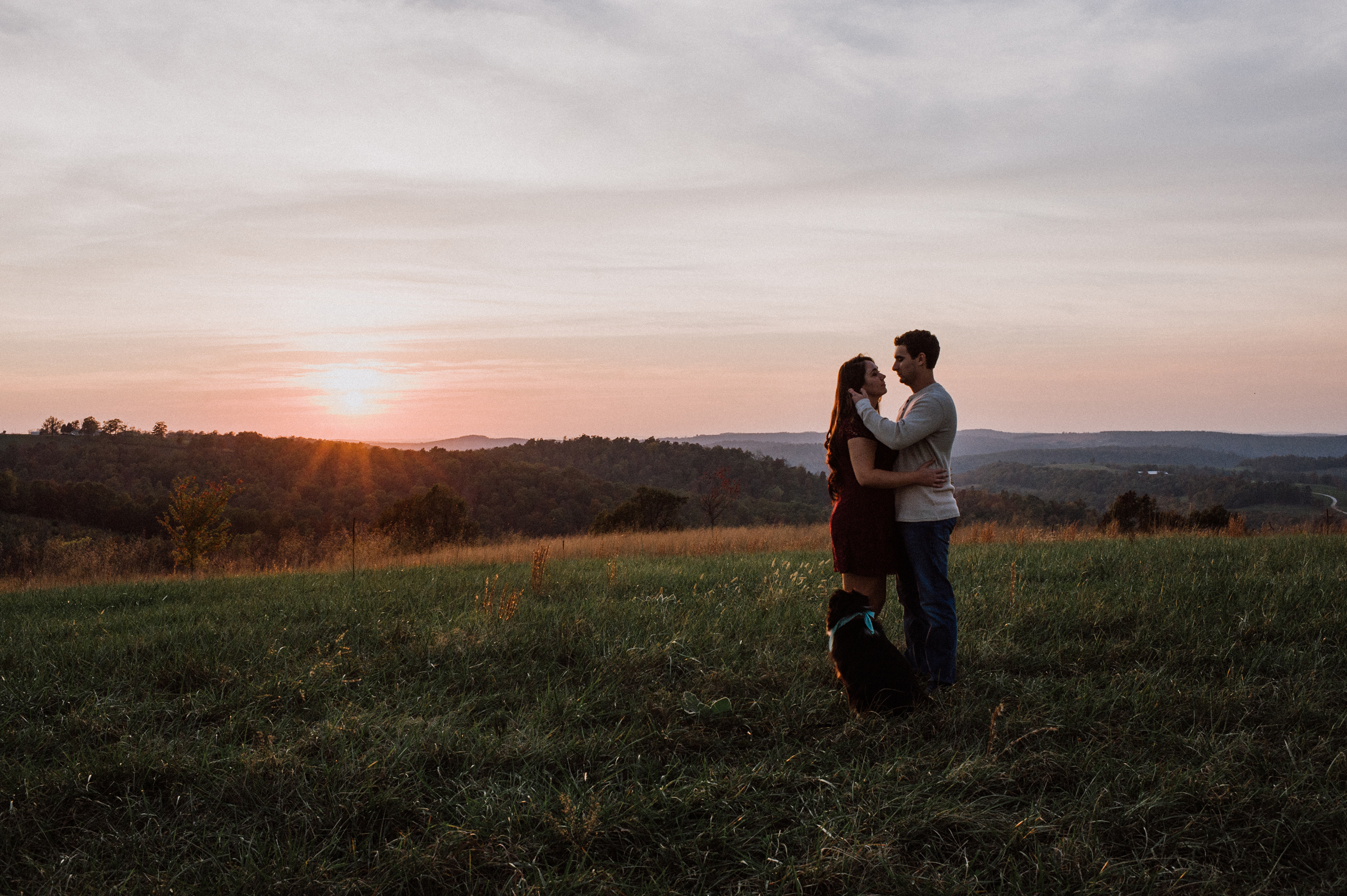 Couple and dog at sunset on mountain top