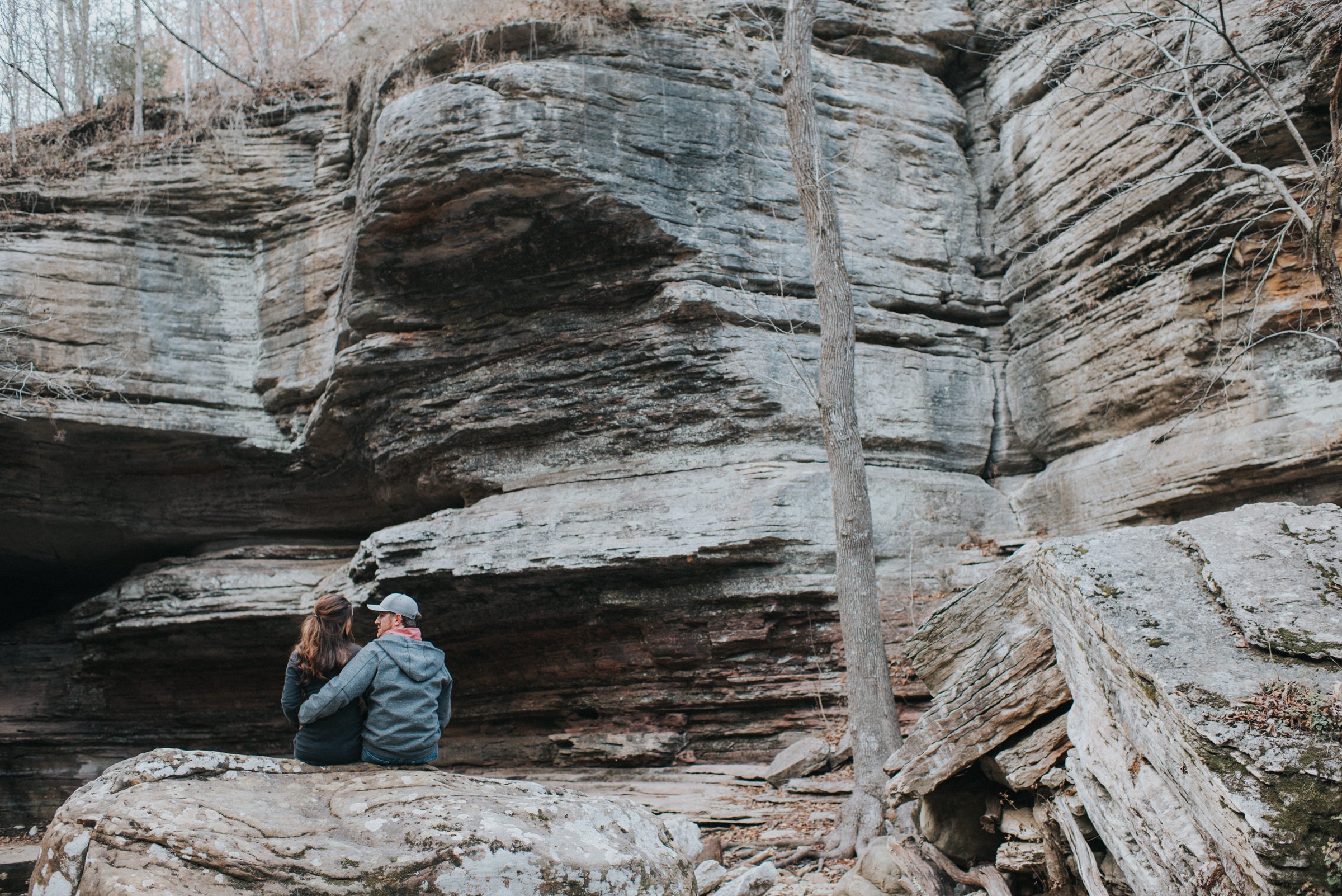 Engagement couple sits among boulders in Lost Valley