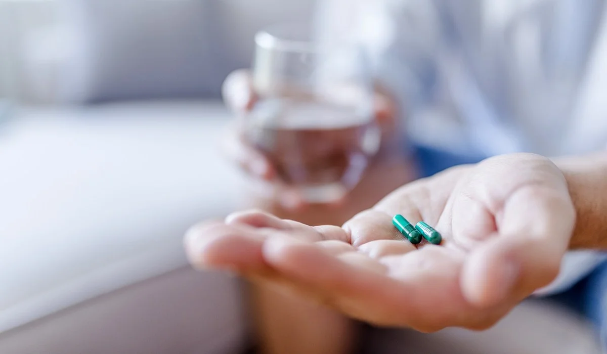 A-person-holding-two-pills-and-a-glass-of-water.jpg